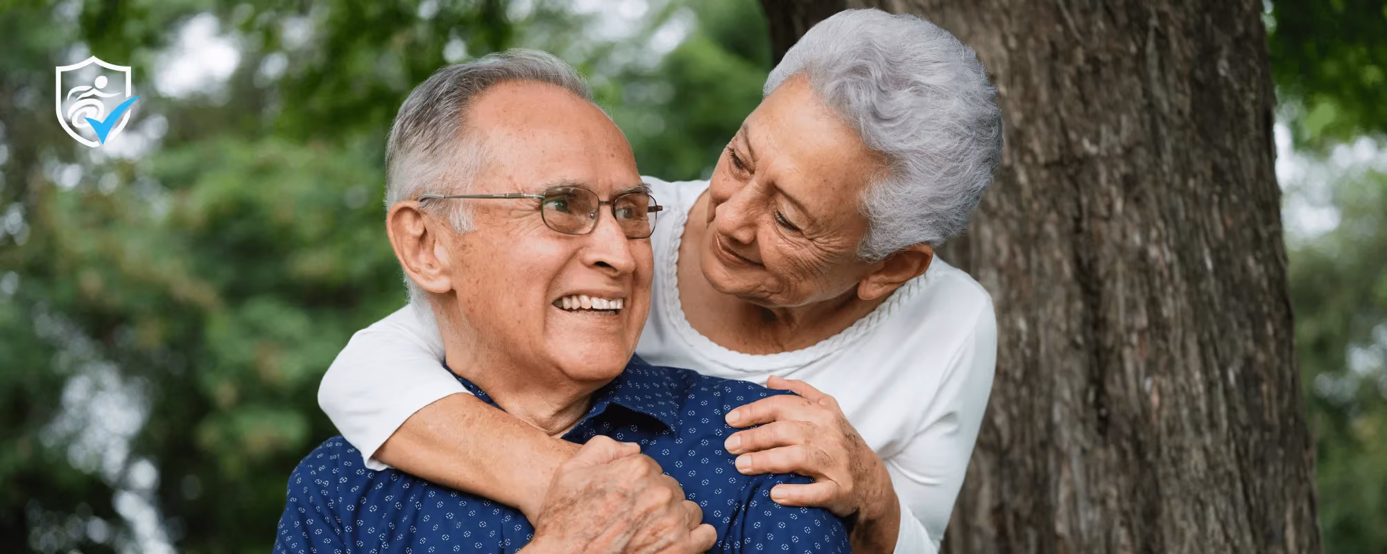 An older woman hugging an older man on a park bench