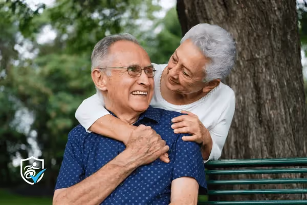 An older woman hugging an older man on a park bench