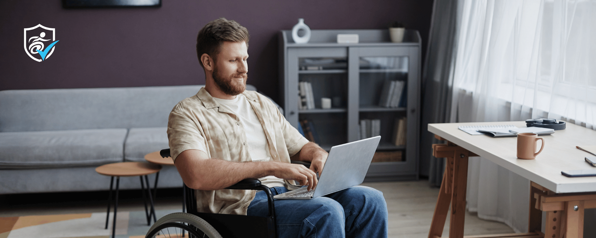 Man in a wheelchair with a laptop on his lap in a sitting room