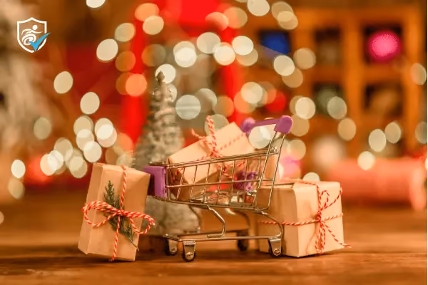 Photo of wrapped christmas gifts next to a mini shopping trolley in front of blurred glowing lights