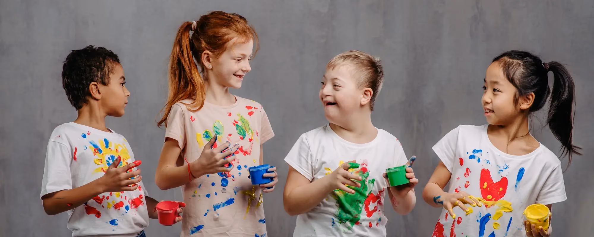Four children standing in a line doing finger painting
