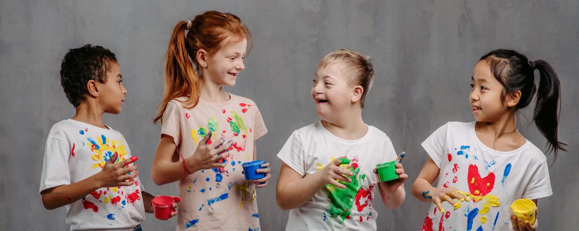 Four children standing in a line doing finger painting