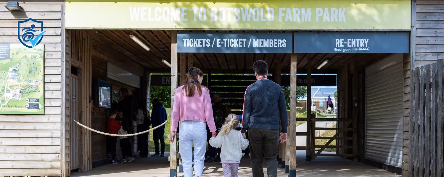 Photo of a woman, man and child walking towards the Cotswolds Farm Park entrance