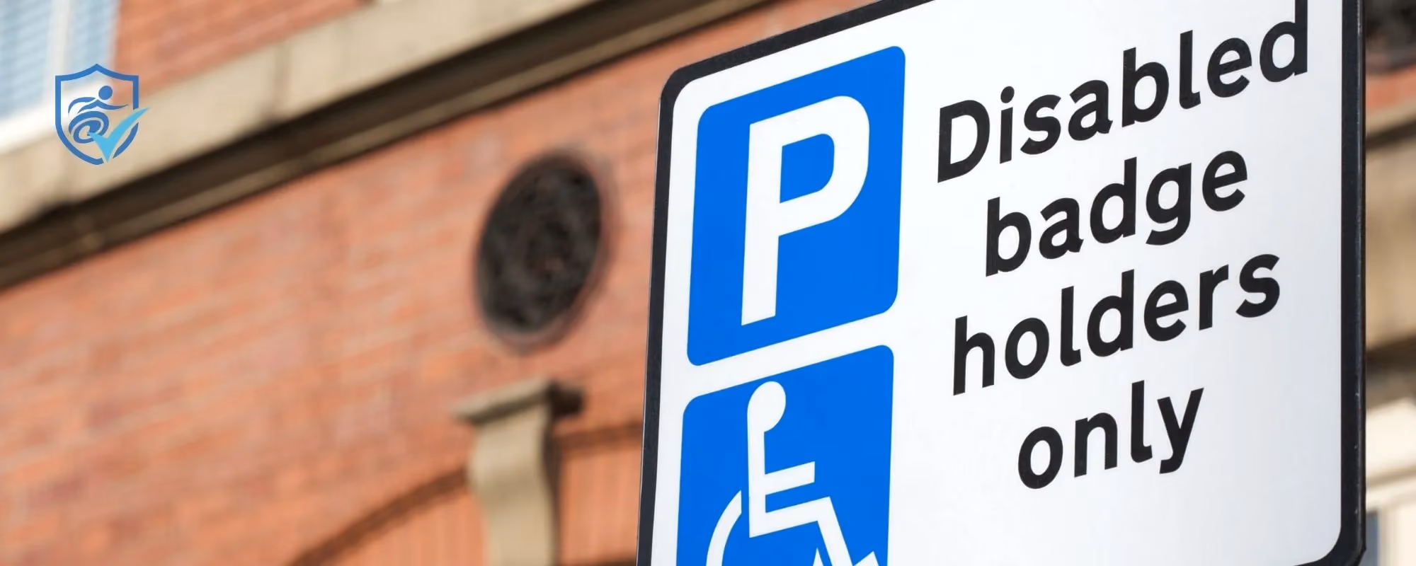 Photo of a disabled parking sign in front of a brick wall
