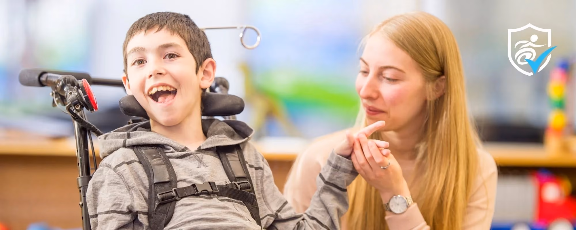 A boy in a wheelchair and a girl sitting next to him, holding his hand