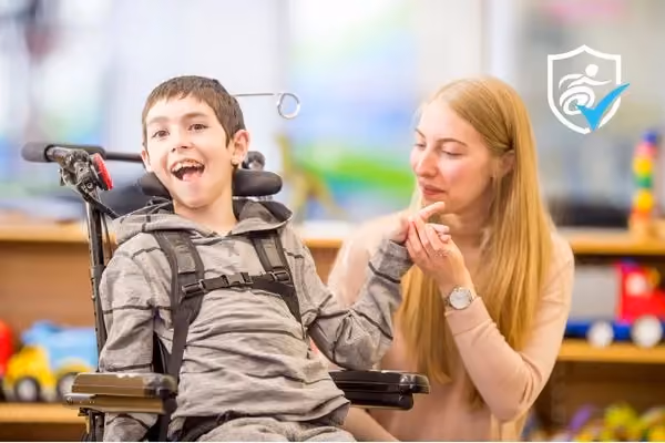 A boy in a wheelchair and a girl sitting next to him, holding his hand