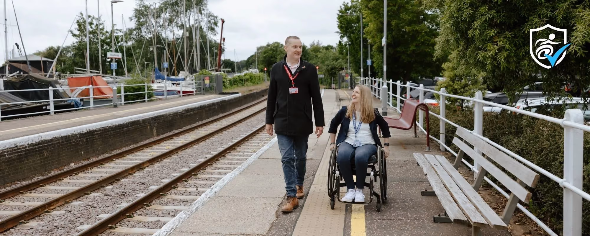 A man and a woman in a wheelchair on a train station platform