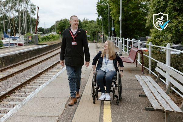 A man and a woman in a wheelchair on a train station platform