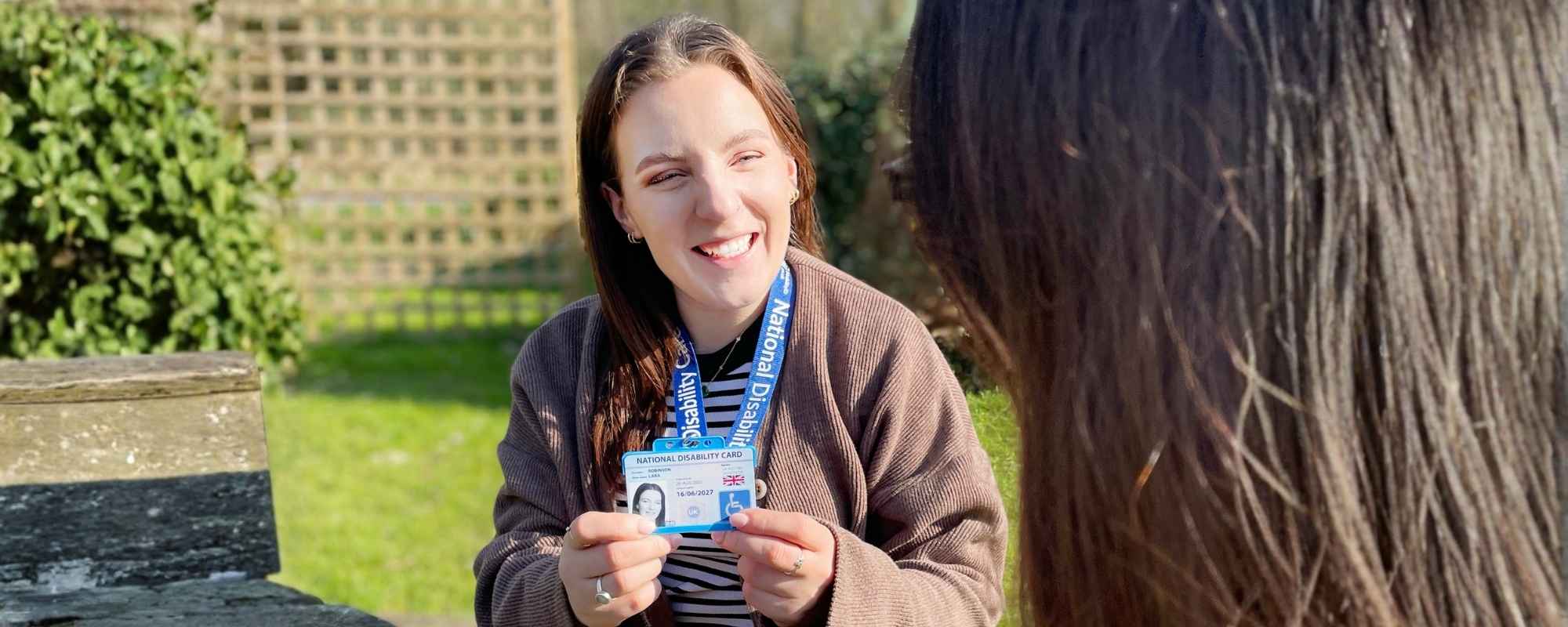 Photo of Lara holding the National Disability Card