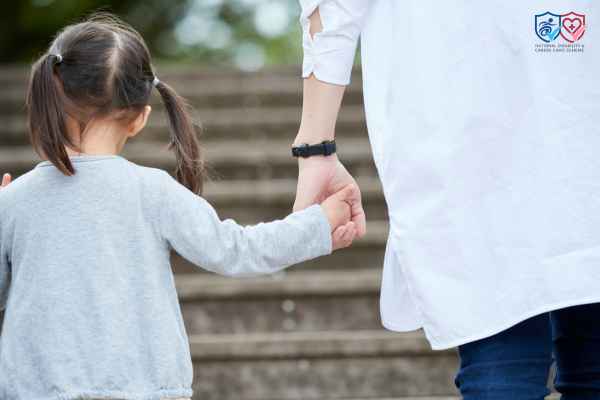 A woman and a little girl are walking and holding hands.