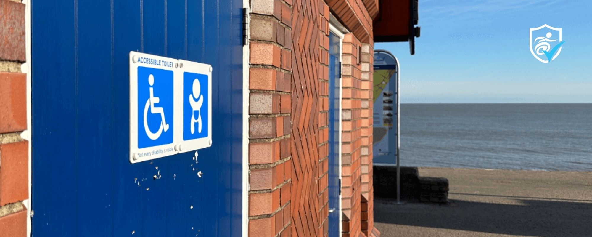 Photo of a disabled toilet with a blue door and the beach and sea in the background