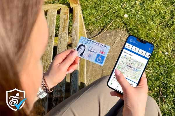 woman holding her national disability card next to her phone with the disabilityID app open