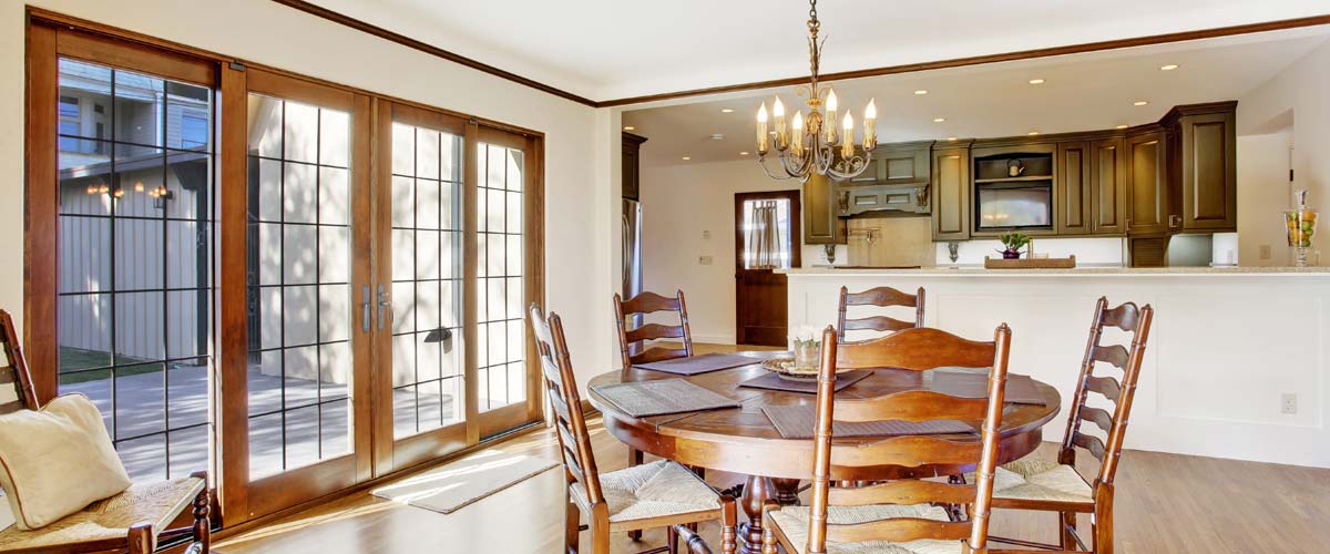 Wooden-framed glass patio doors leading to an outdoor deck area from a dining room.