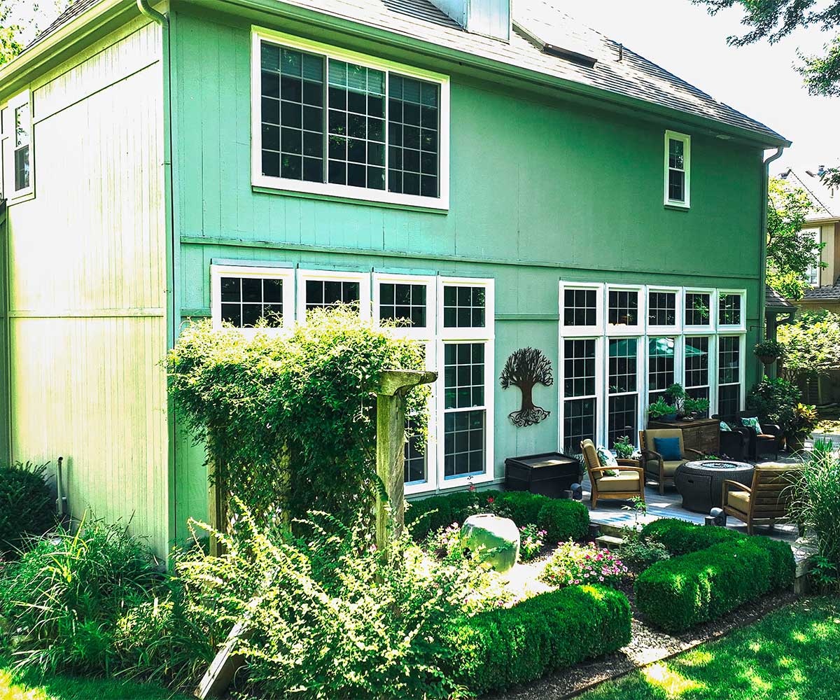 Green home with large replacement windows enhancing natural light and garden view