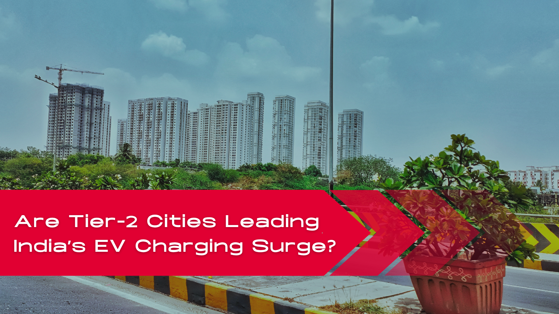 Skyline of a Tier-2 Indian city with high-rise buildings and greenery, highlighting urban growth and the rise of EV charging infrastructure.