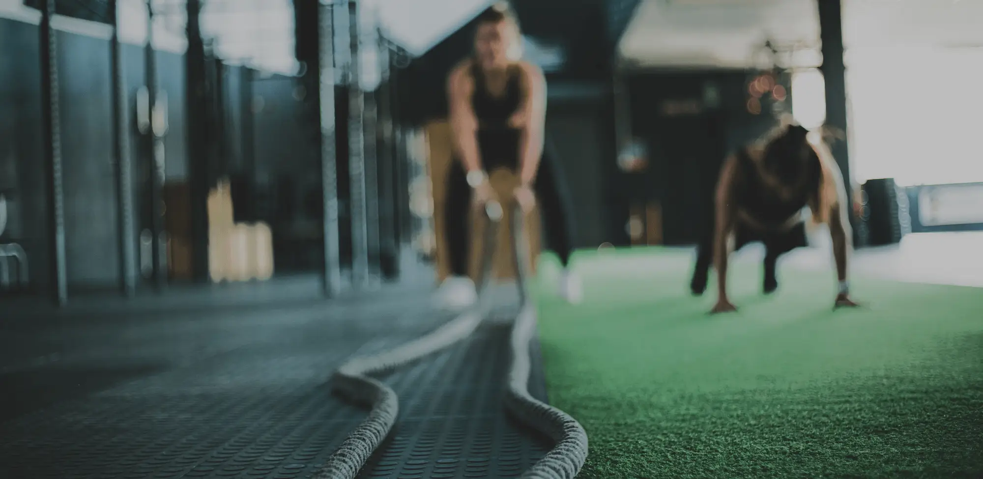 Blurry image of trainers exercising with ropes in a gym, symbolising health and fitness coaching.