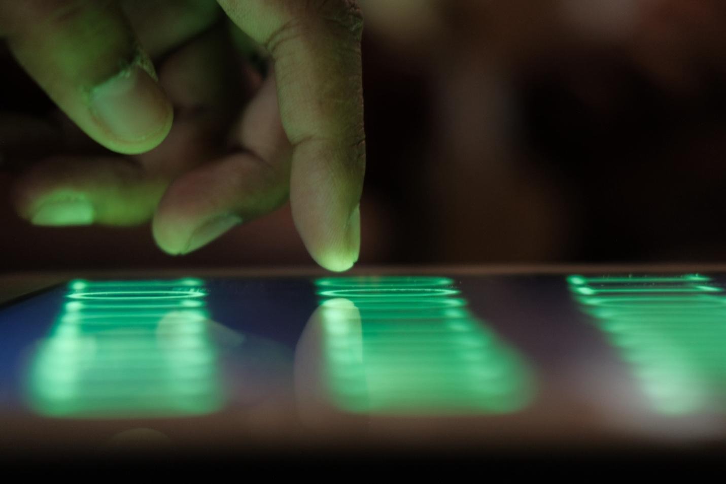 A finger pointing on a tablet with green neon lights