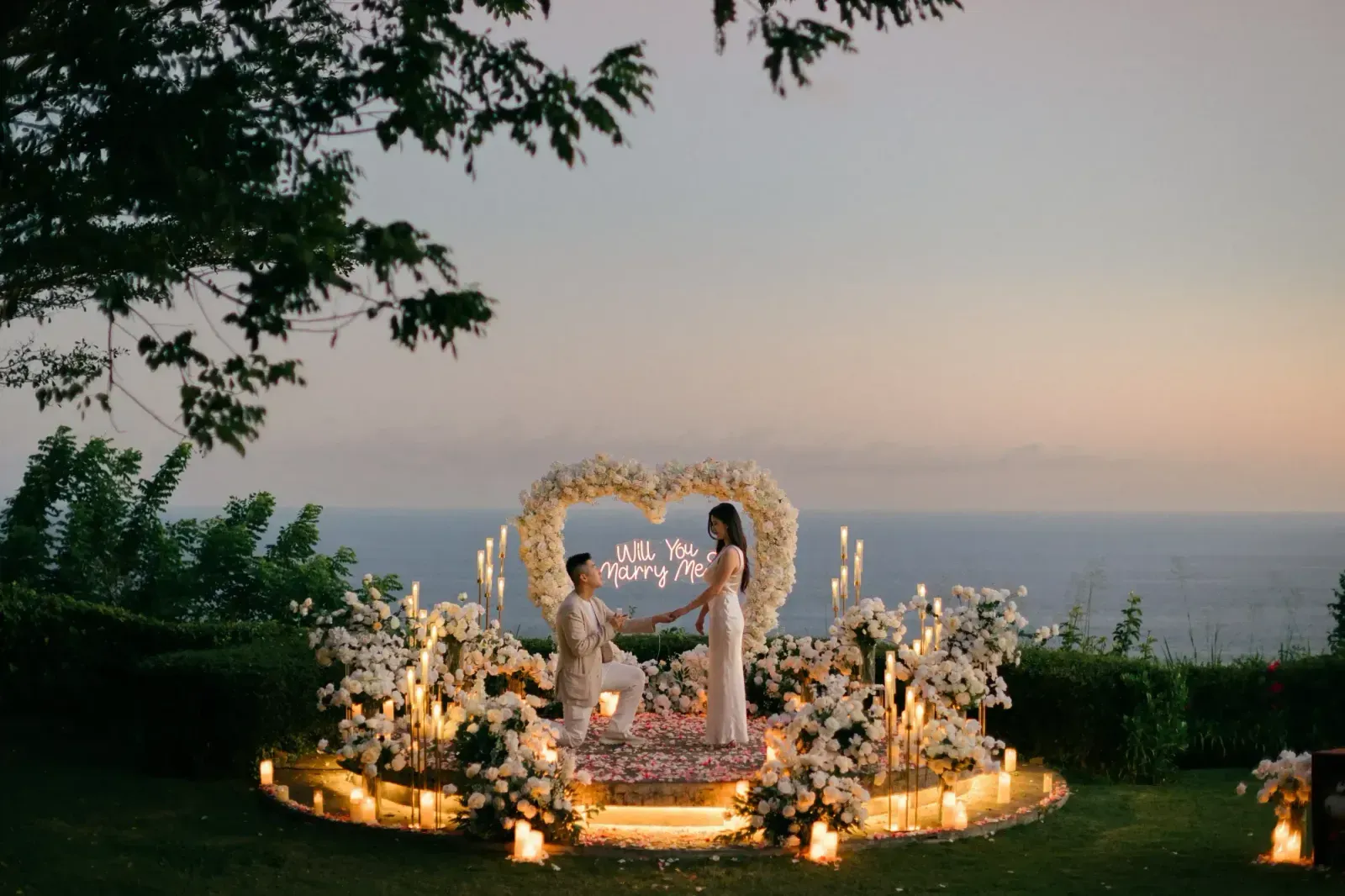 Cliffside heart-arch proposal moment overlooking the ocean in Bali at dusk, arranged by Forever Promises