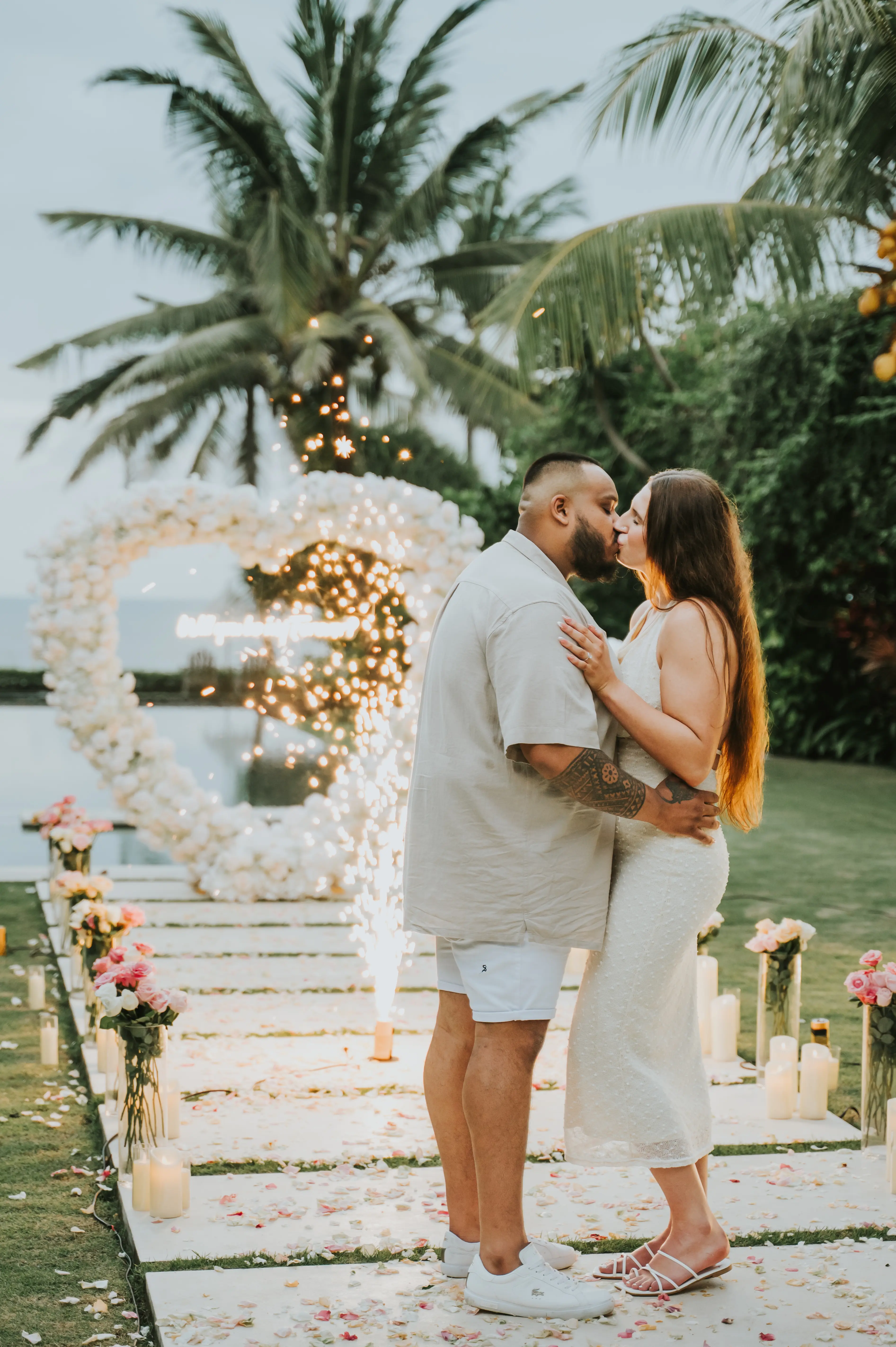 Emotional proposal moment in Bali with flower arch and couple hugging
