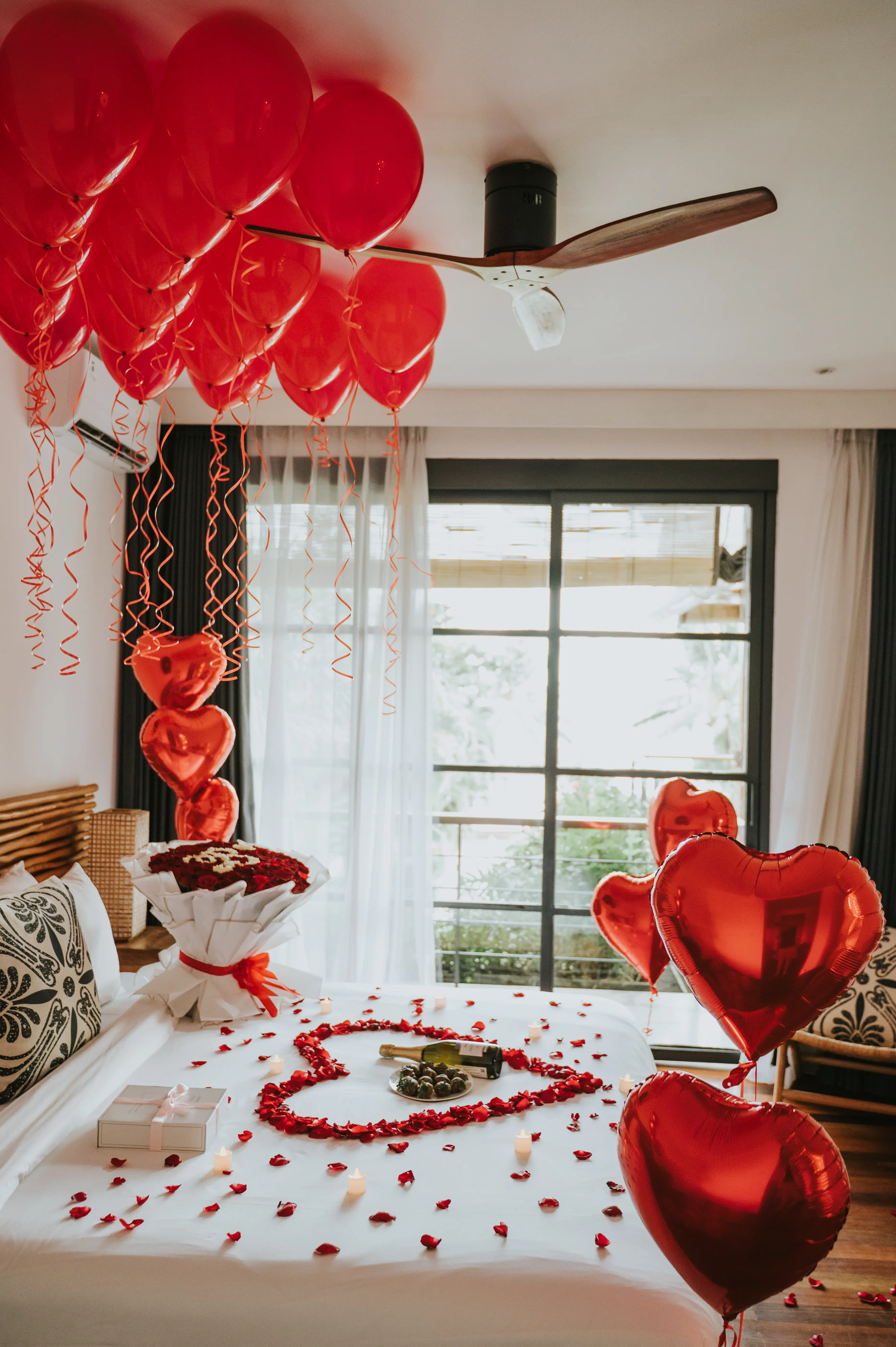Romantic bedroom decoration with red balloons and rose petals for surprise proposal in Bali