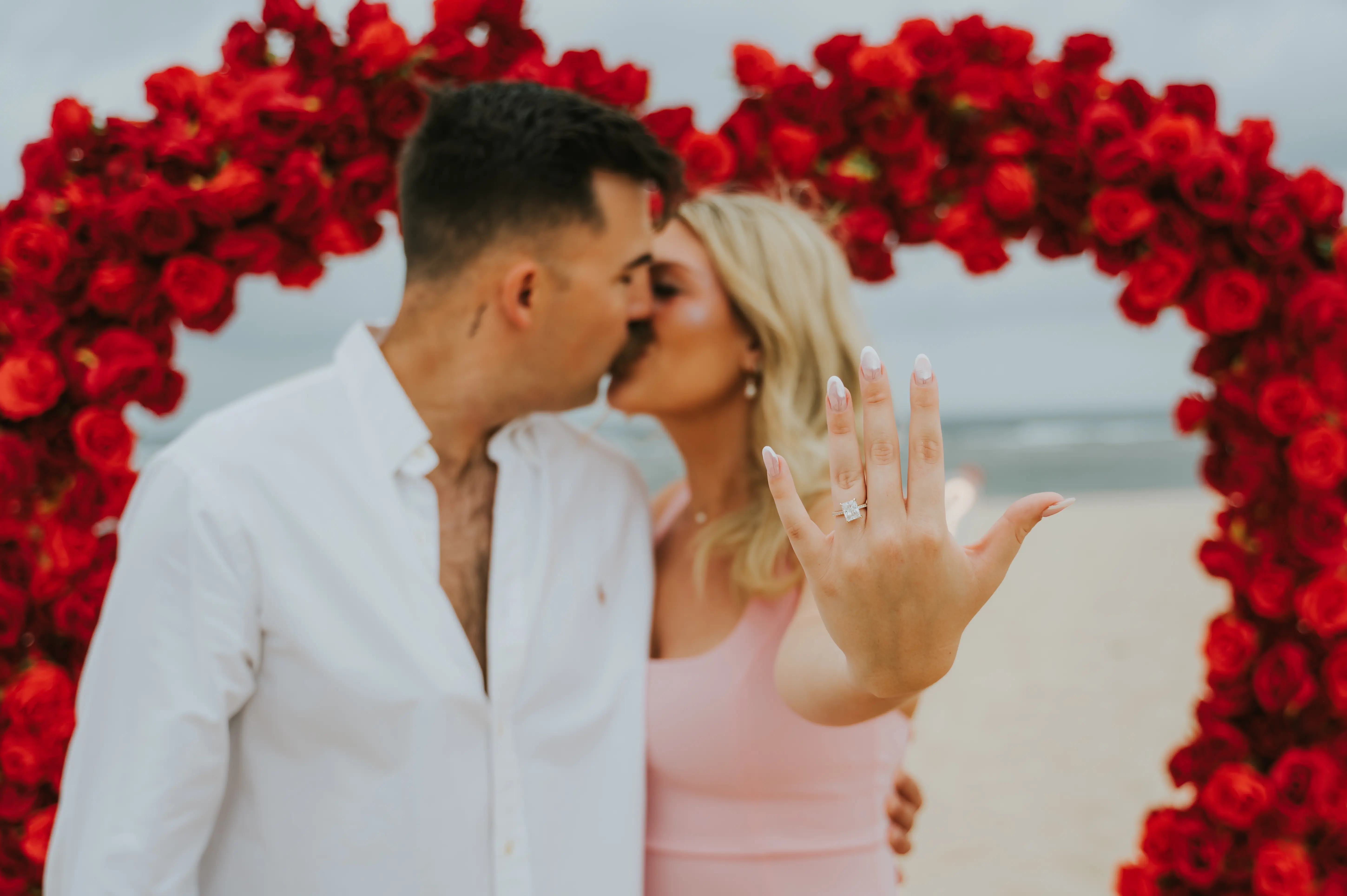 Just engaged couple kissing in front of floral heart arch on Bali beach