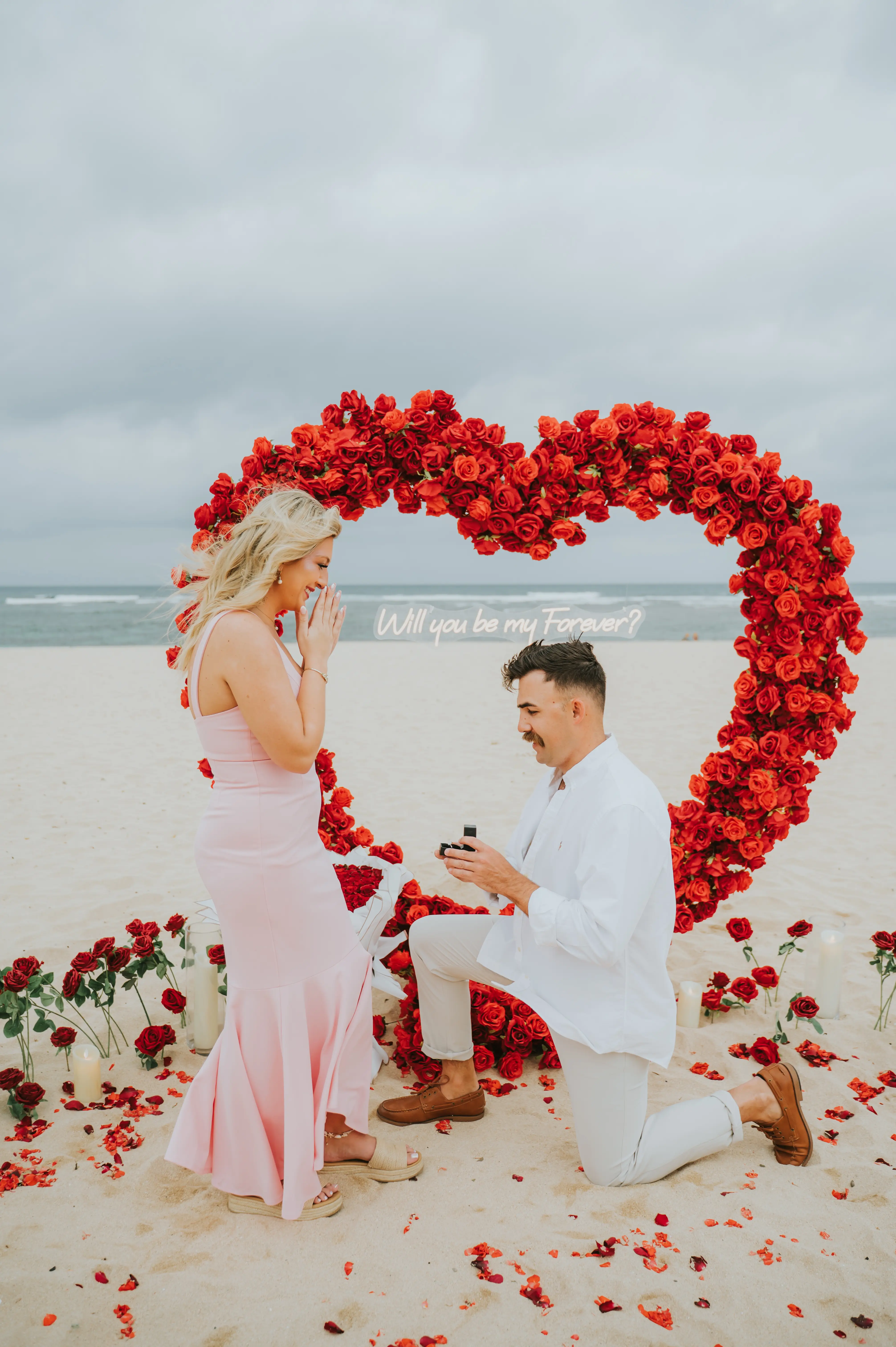 Emotional proposal moment with couple in front of rose heart arch in Bali