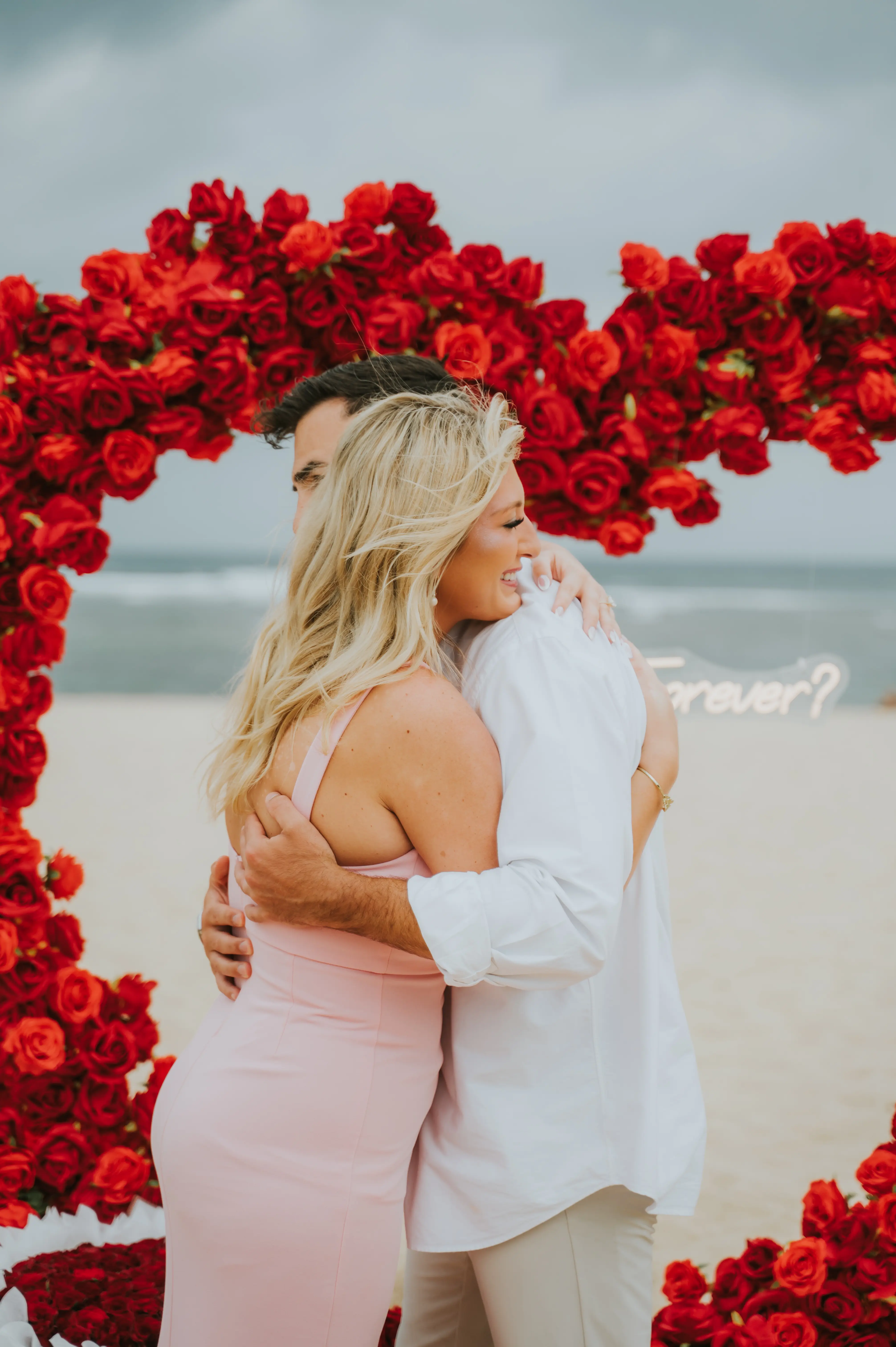 Luxury beach proposal setup in Bali with heart arch and floral decorations