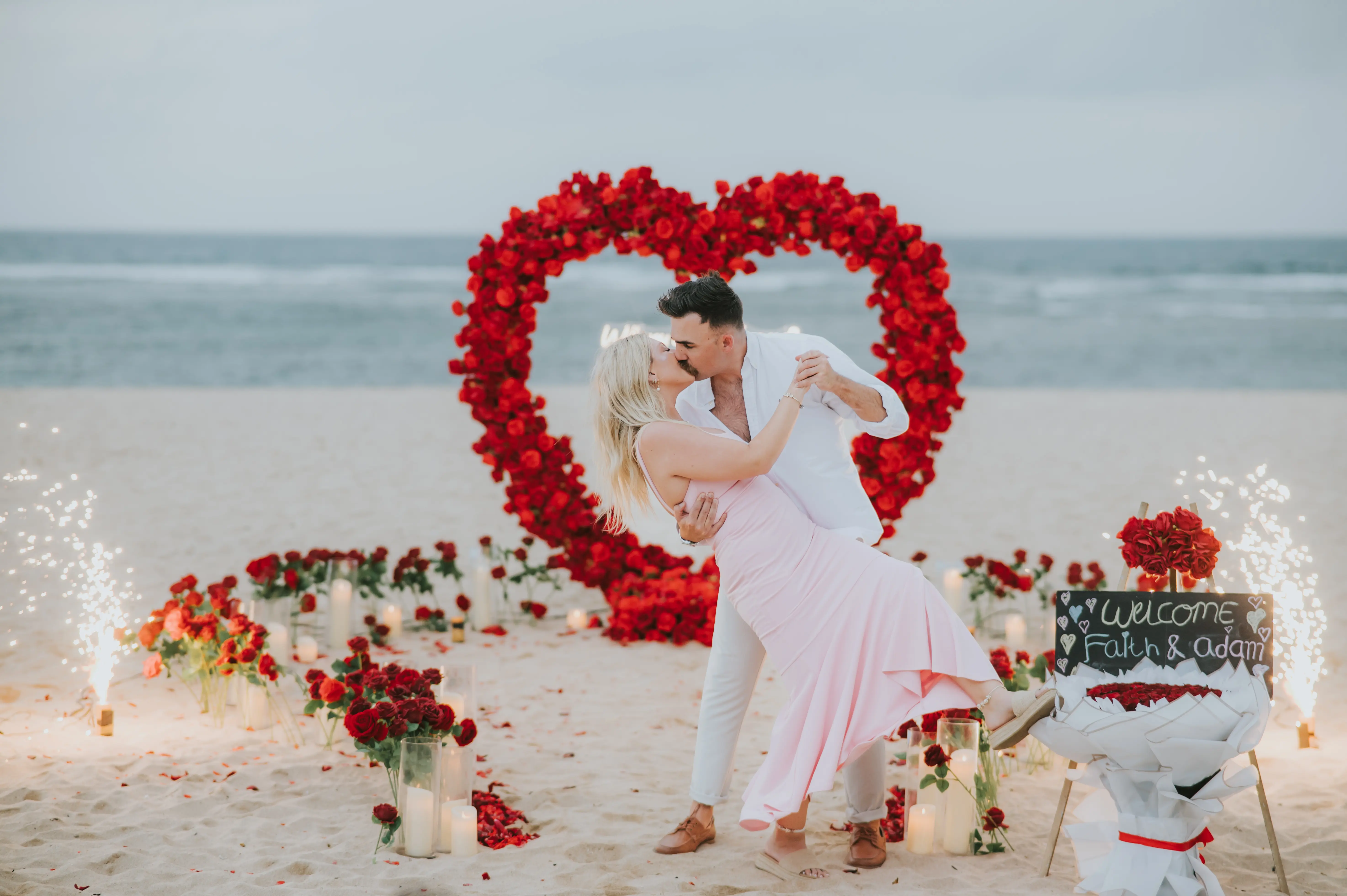 Romantic beach proposal setup with red heart flower arch in Bali