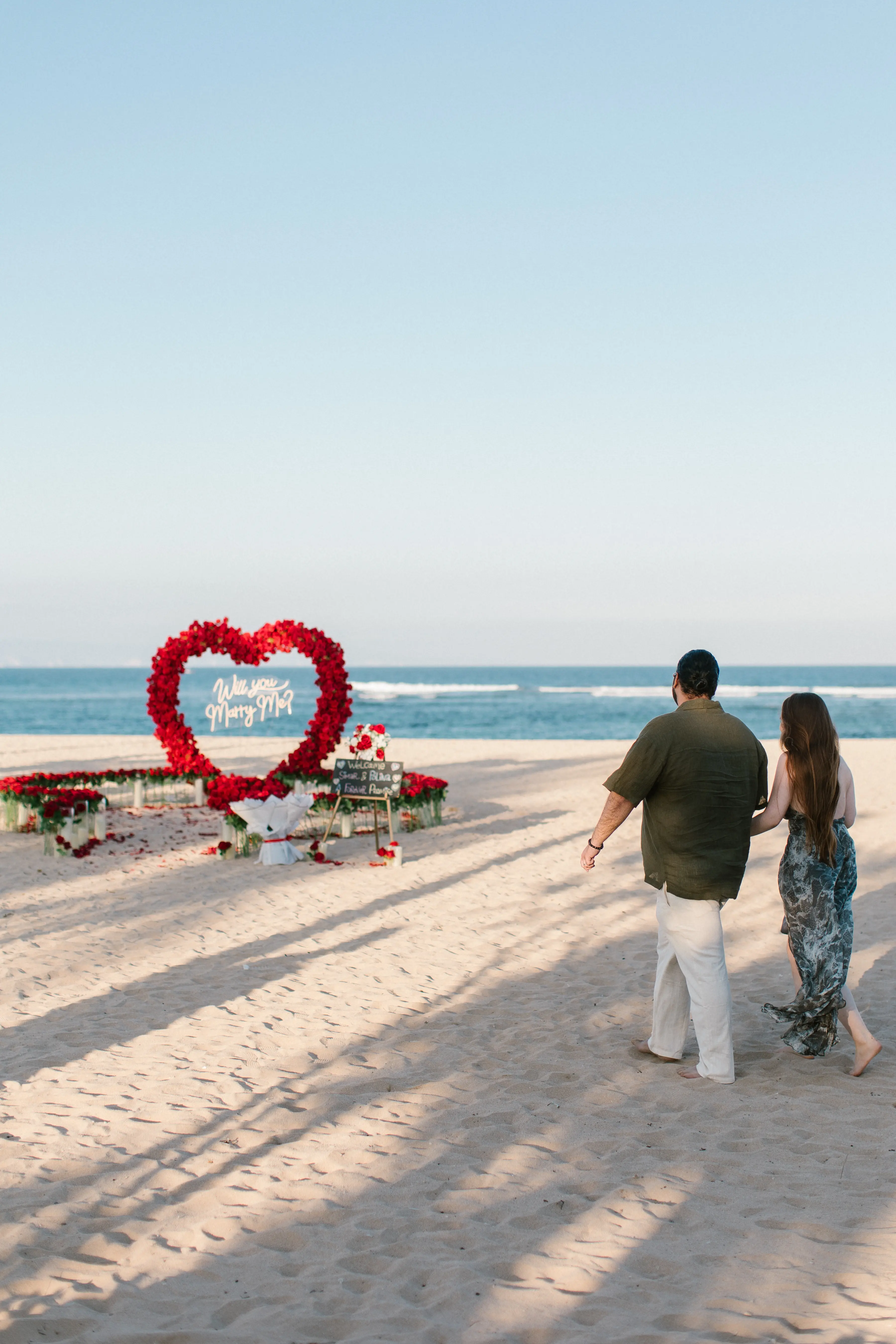 Couple walking towards beach proposal setup in bali 
