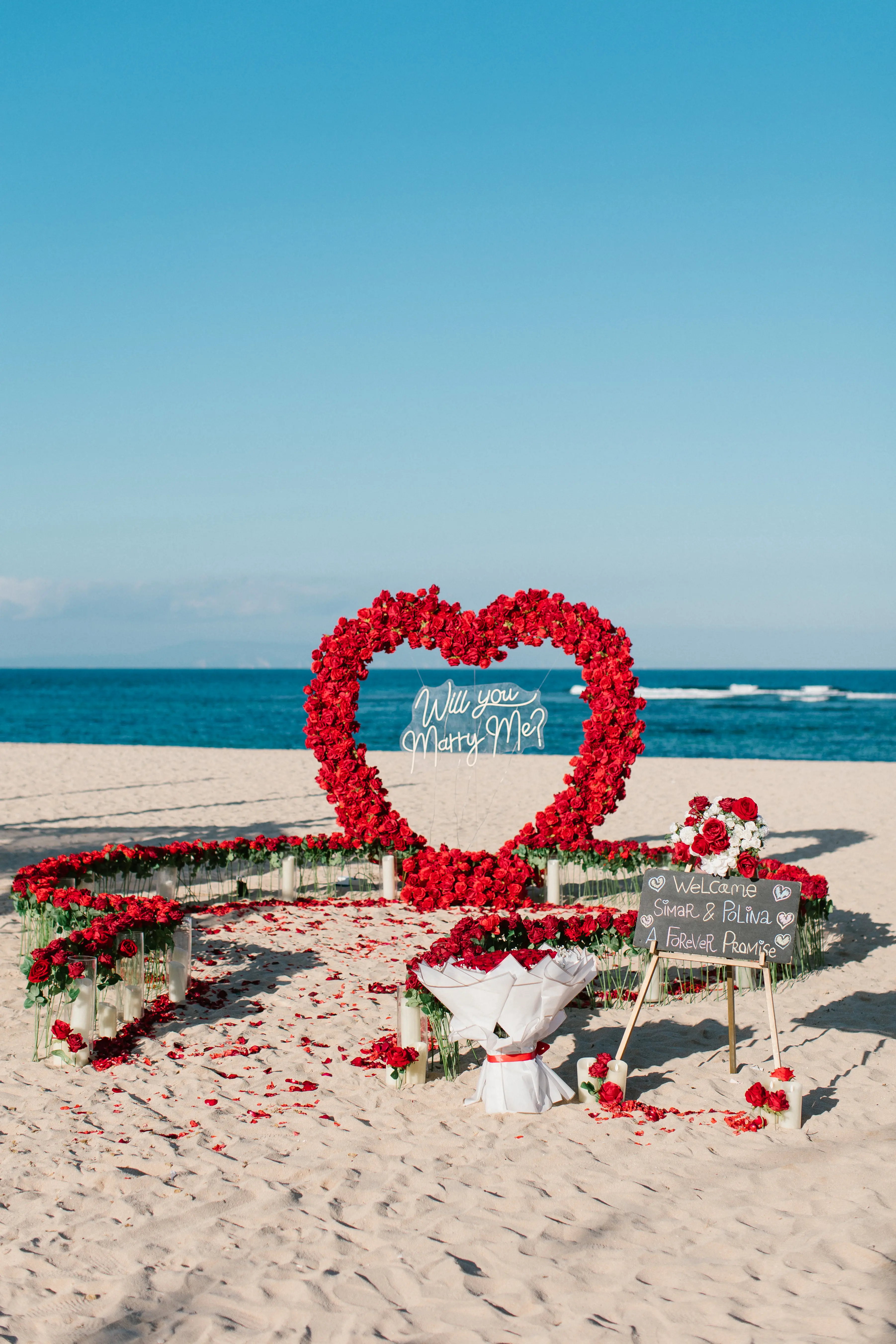 Bali beach proposal setup with heart-shaped flowers and candles