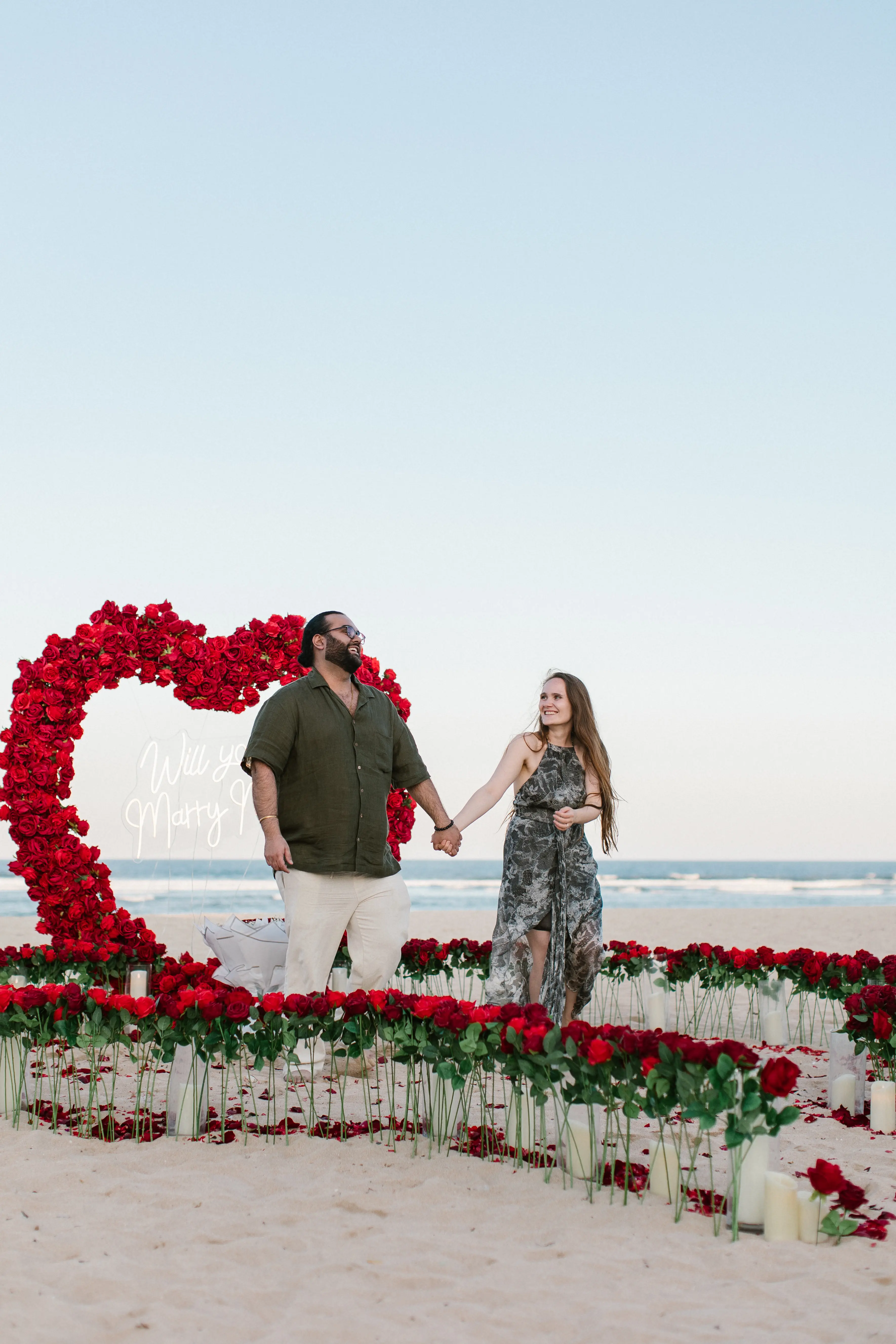 Romantic Bali beach engagement with floral heart backdrop