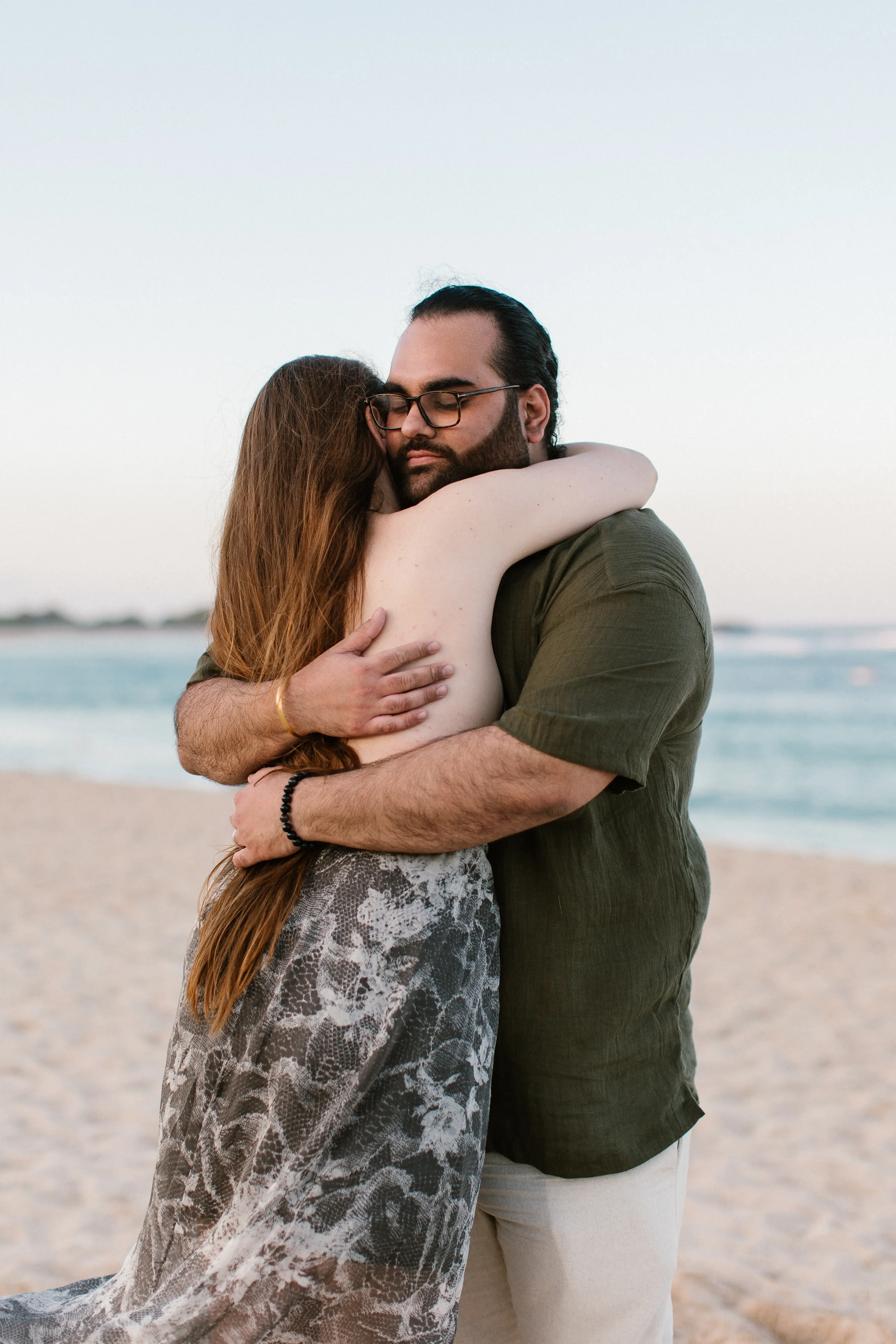 Couple hugging during surprise beach proposal in Bali