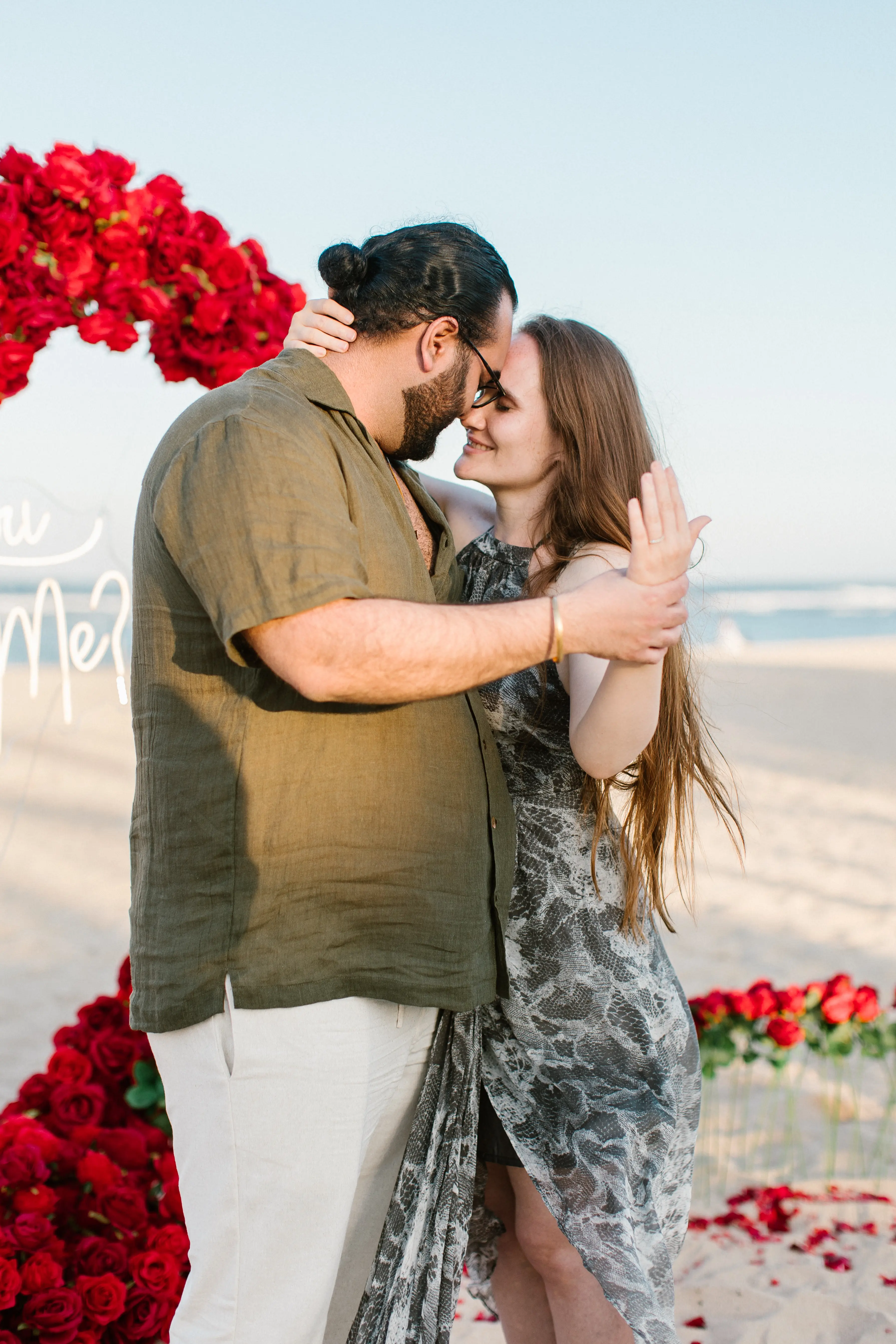 Proposal moment in Bali with couple embracing in front of romantic decoration