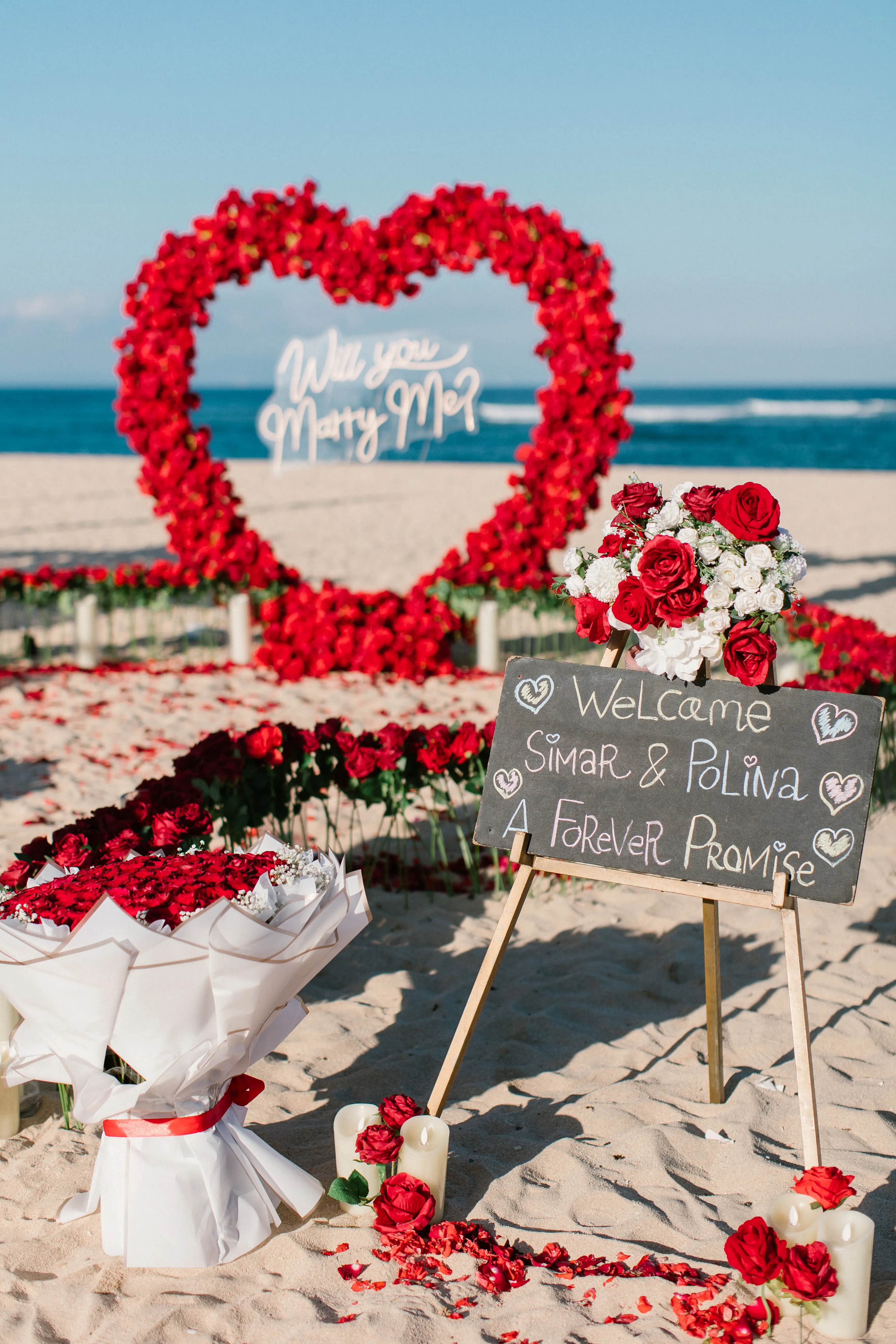 Bali beach proposal setup with red roses, candles, and heart centerpiece