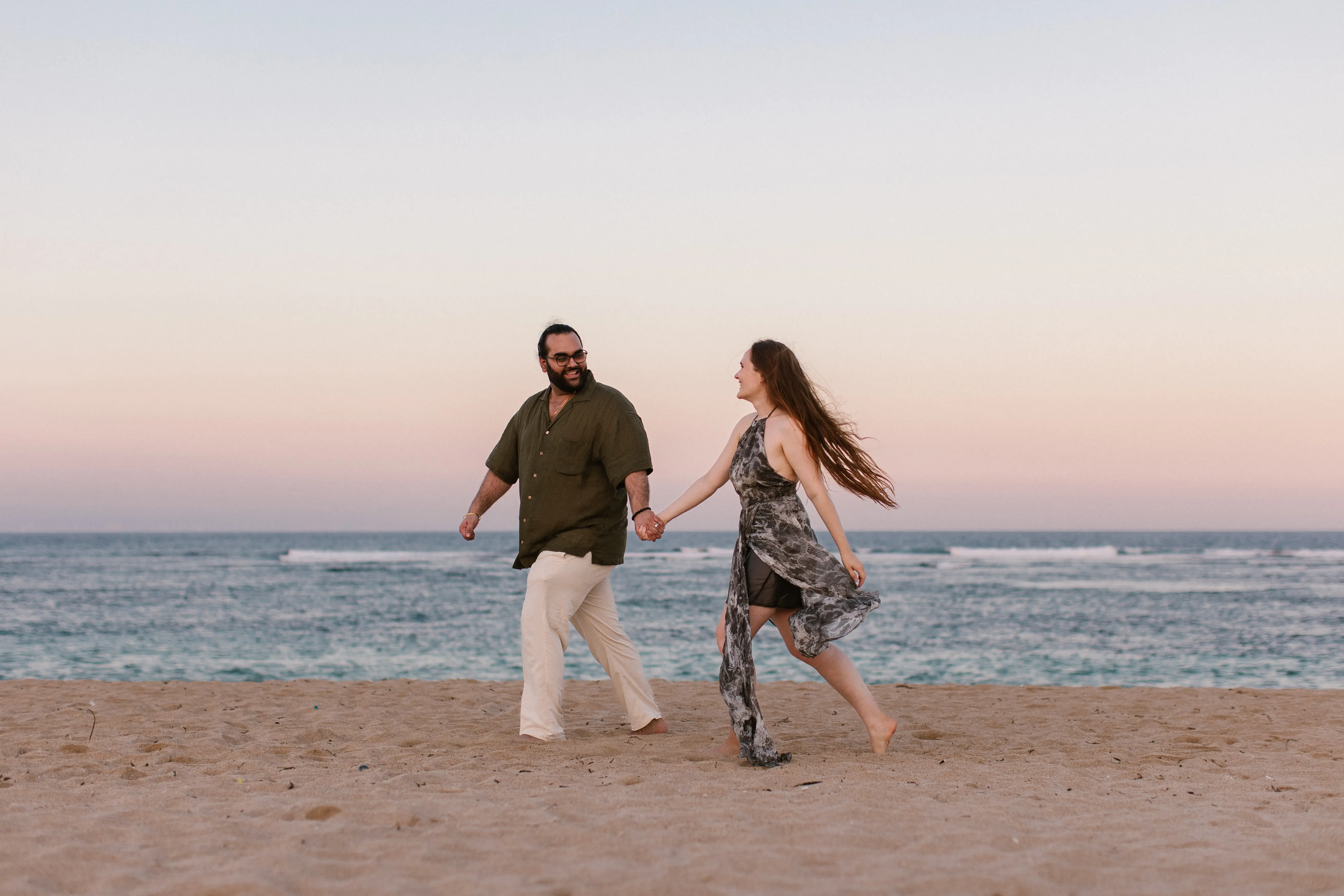 Couple walking hand in hand on Bali beach after proposal