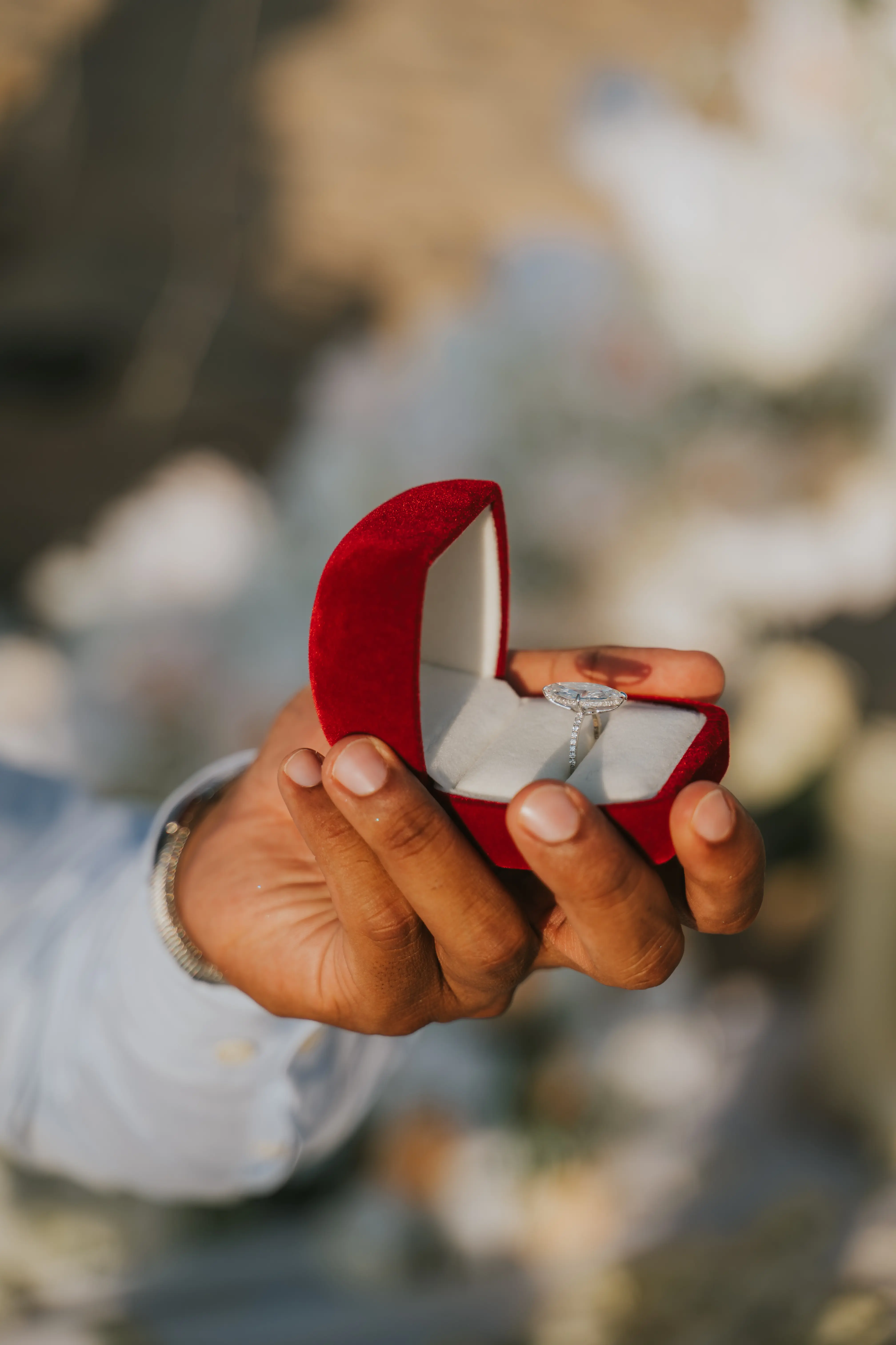 Red ring box with engagement ring at beach proposal.