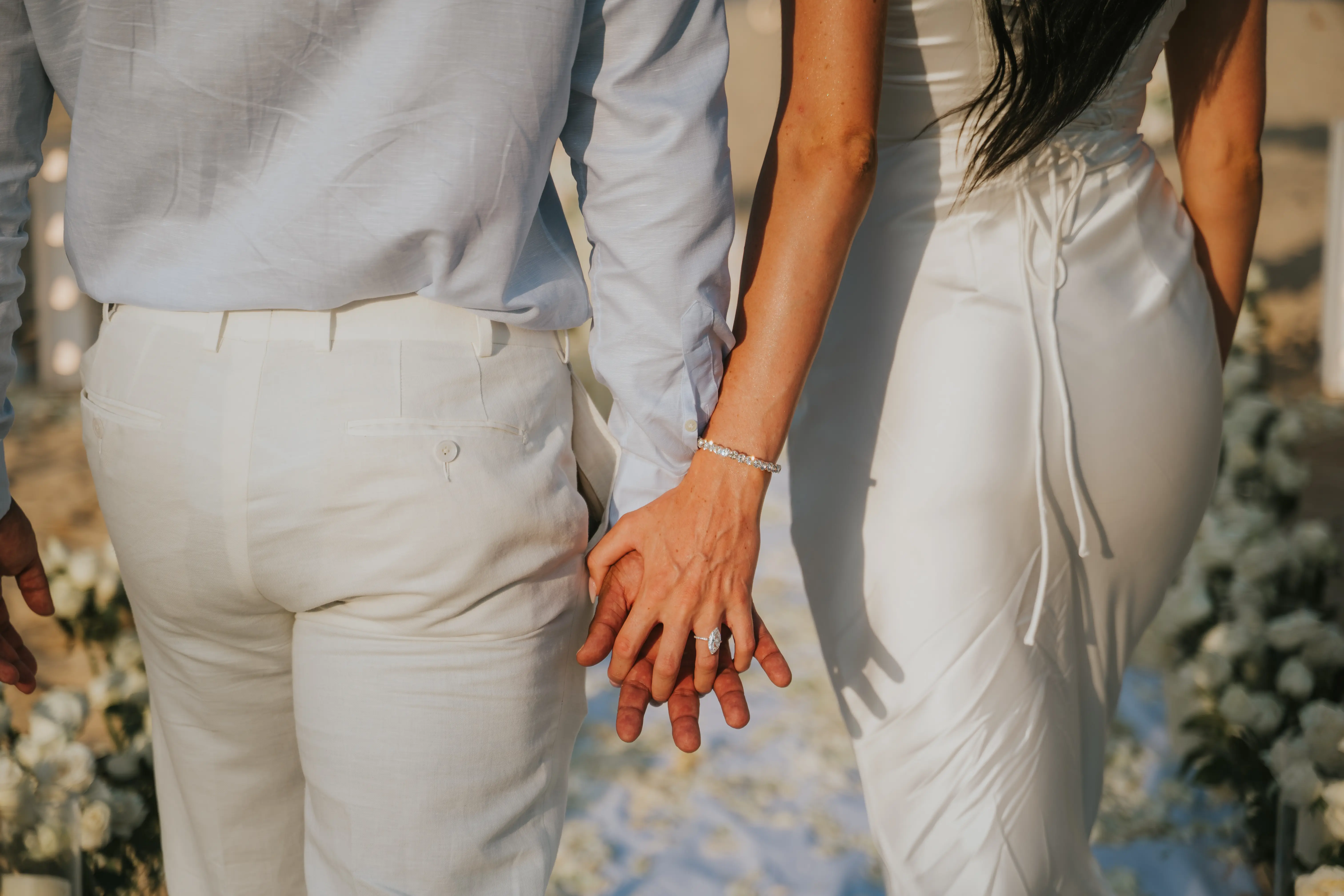 Couple holding hands at beach proposal.