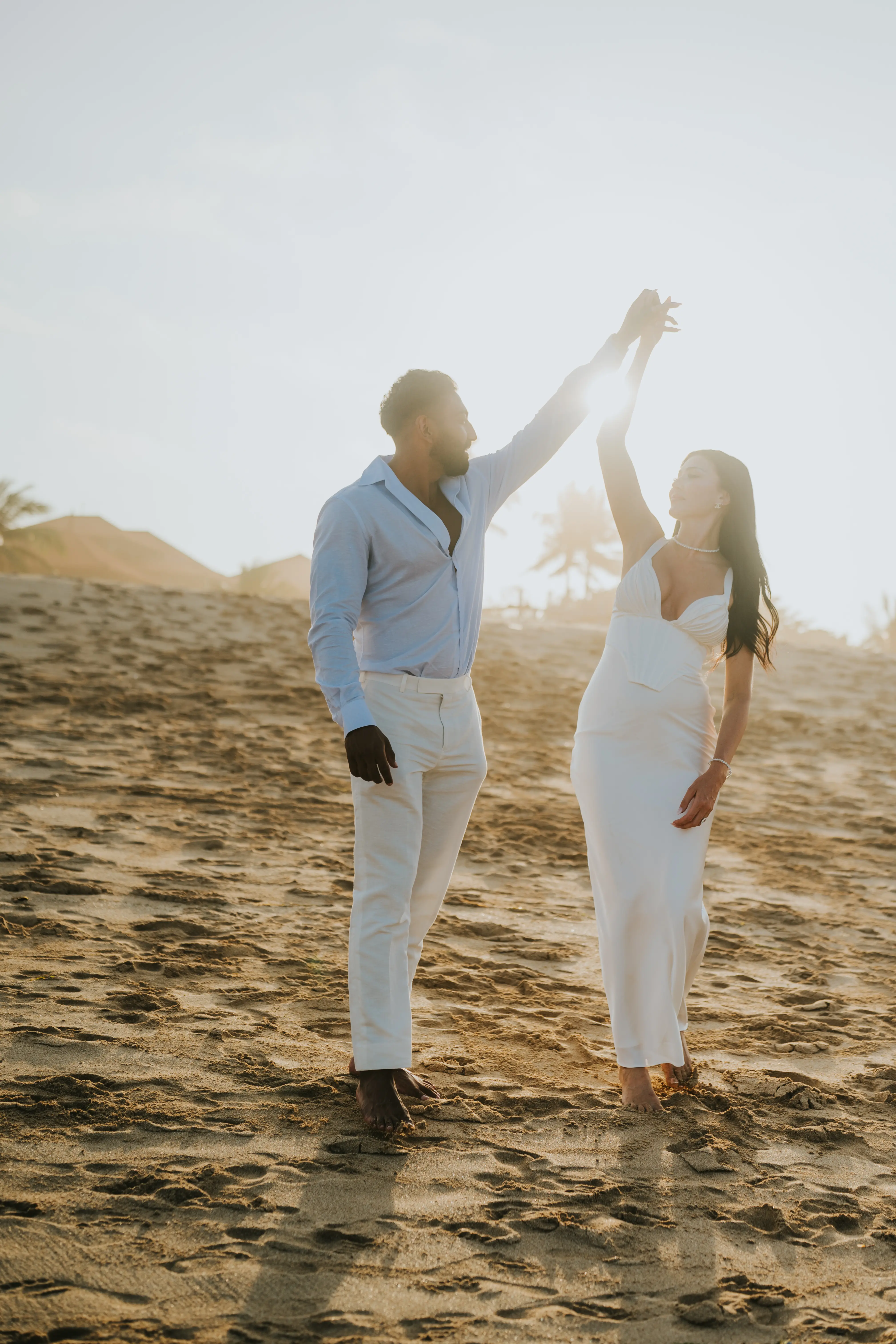 Couple dancing barefoot on Bali beach at sunset.