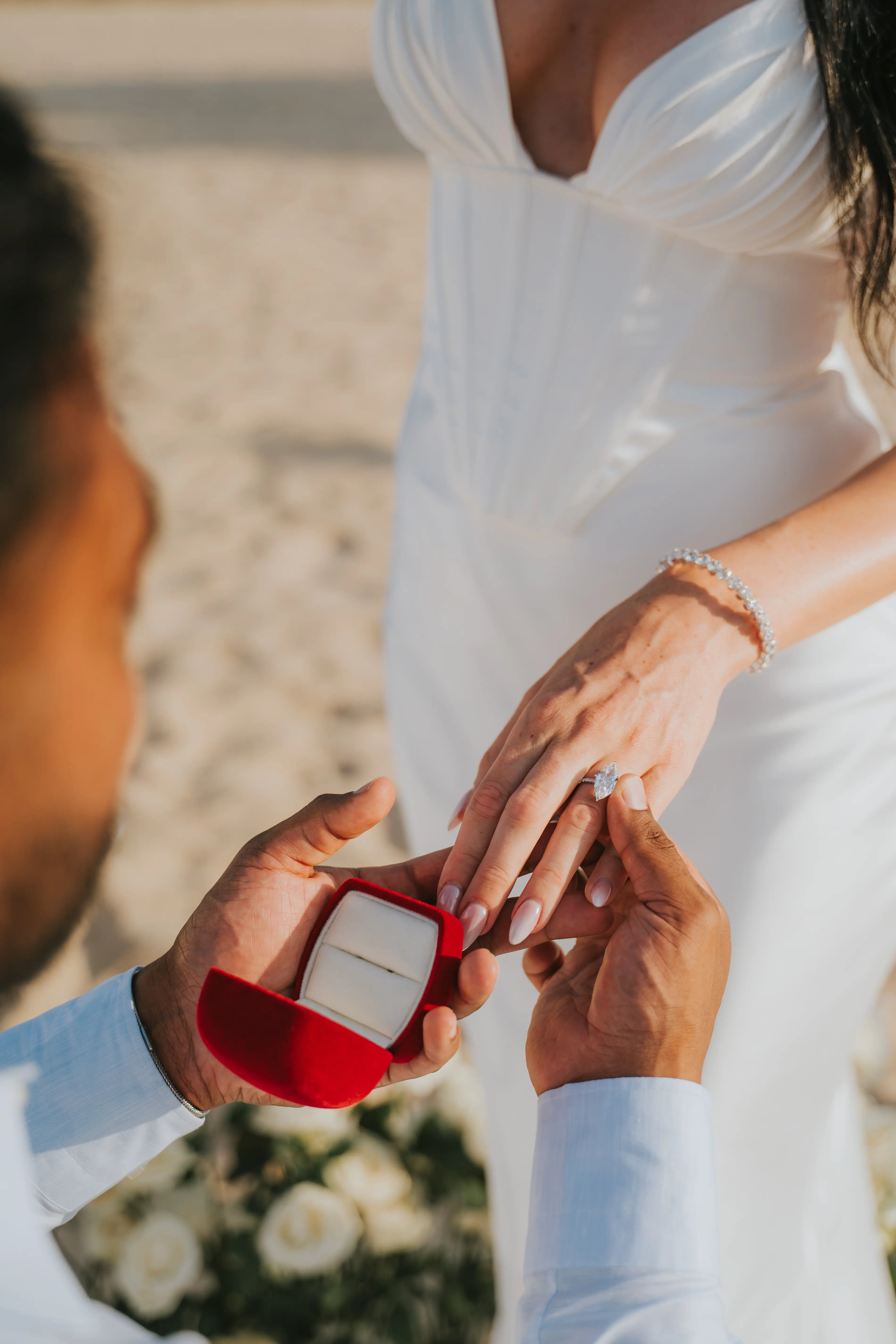 Groom placing engagement ring on bride’s finger.