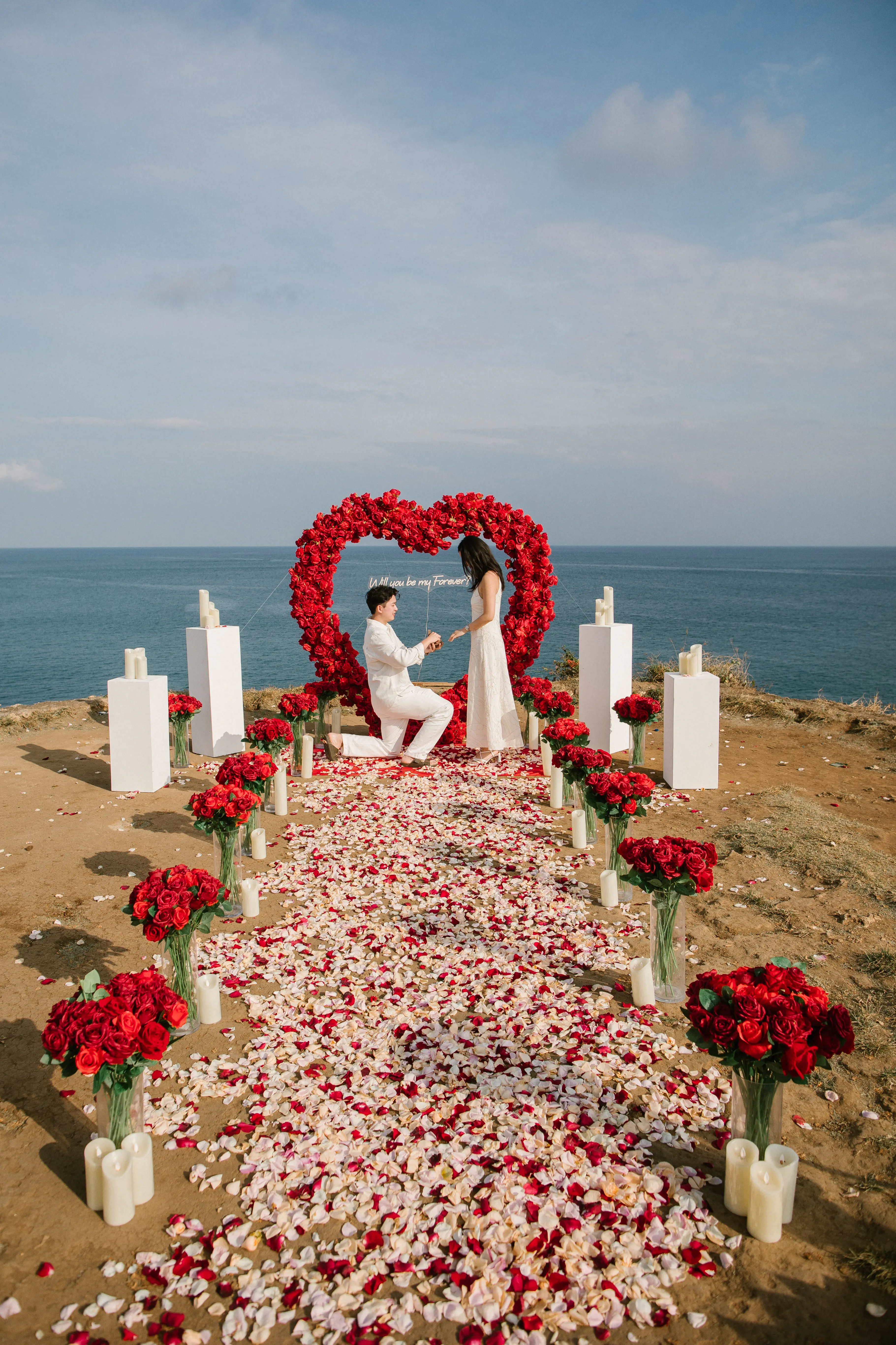Engagement on Bali cliff with dramatic ocean view and flower setup