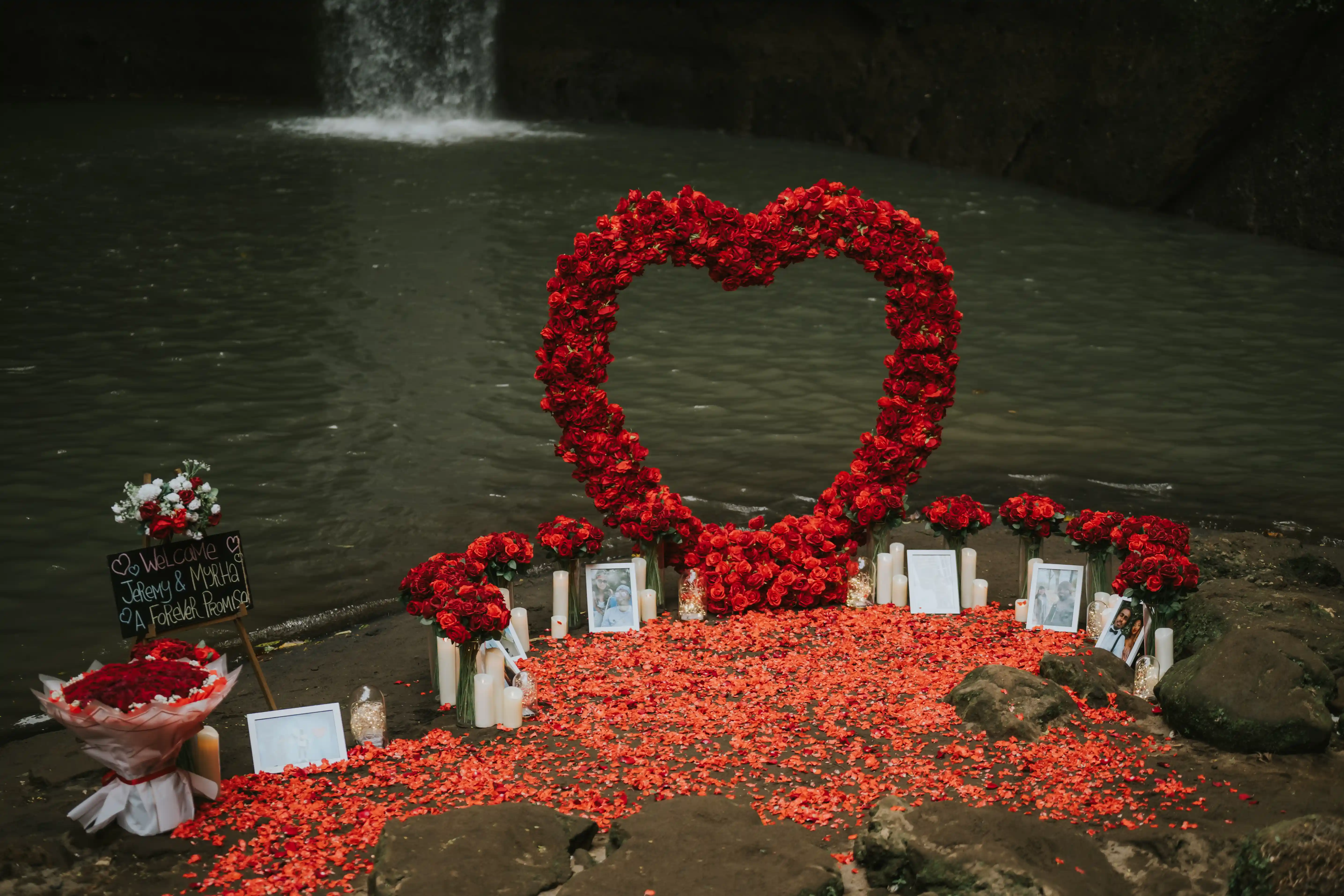 Heart-shaped red flower arch setup for proposal in Bali waterfall