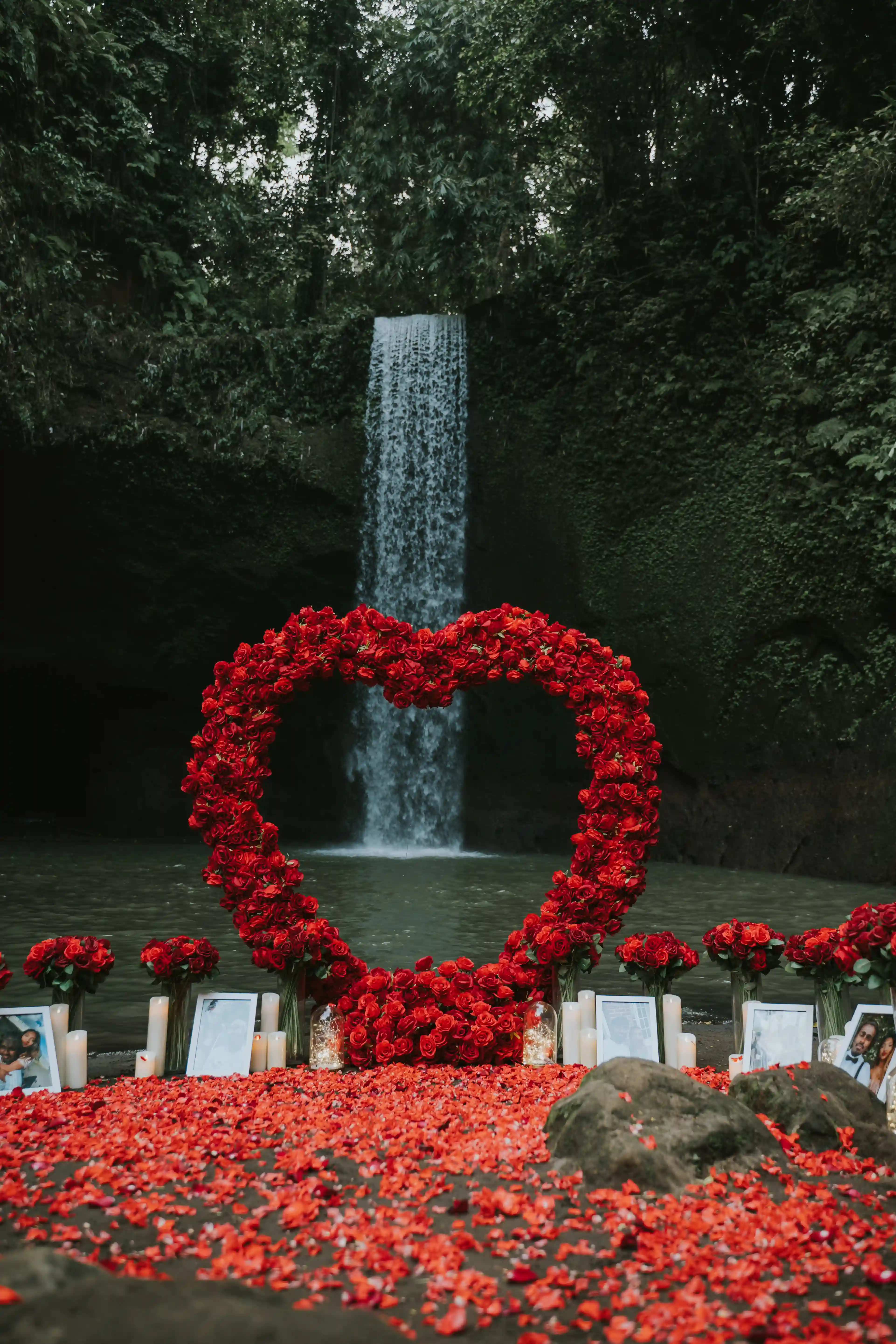 Romantic proposal setup with candles and red flowers at Bali waterfall