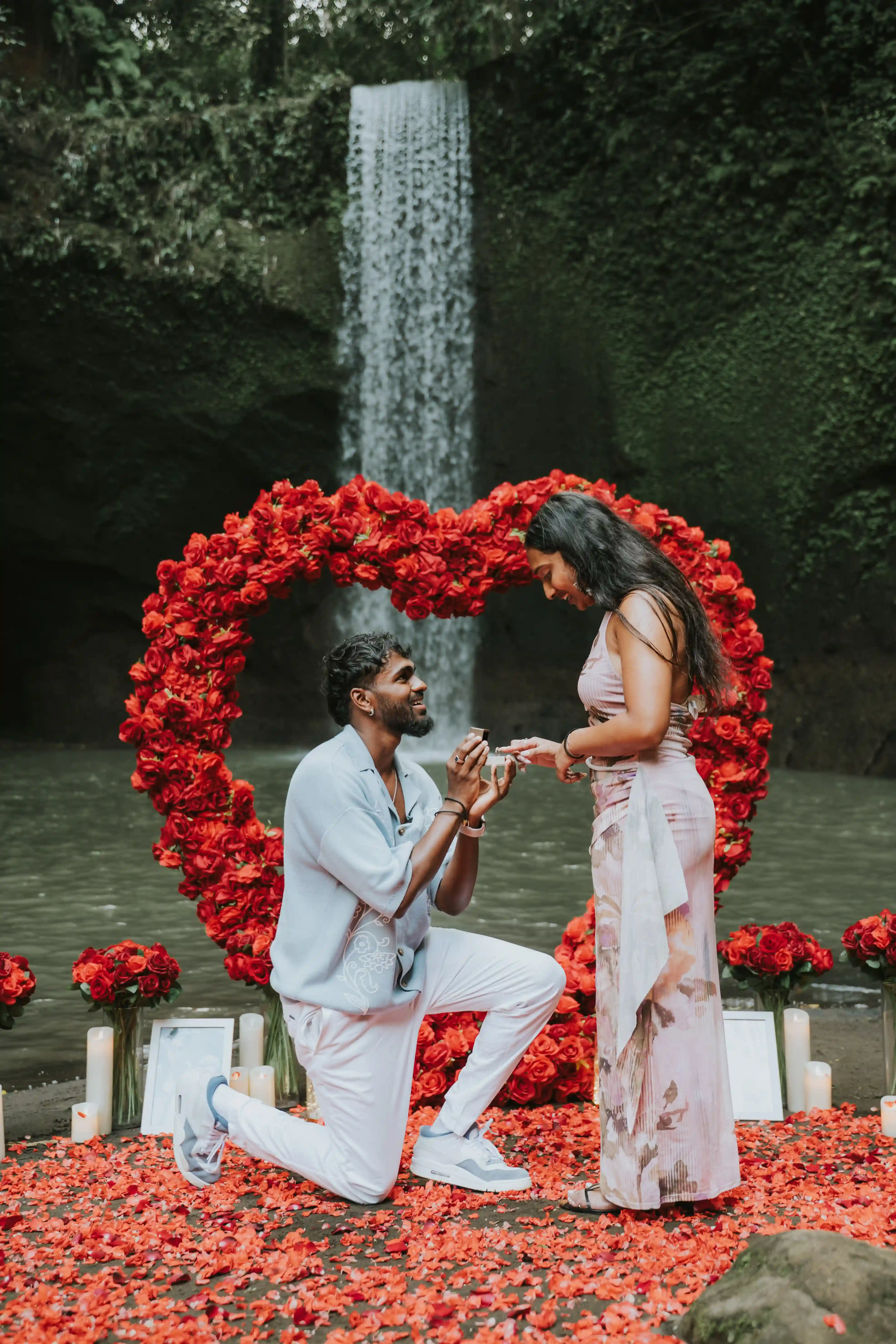 Man proposing with red flower arch at waterfall in Bali