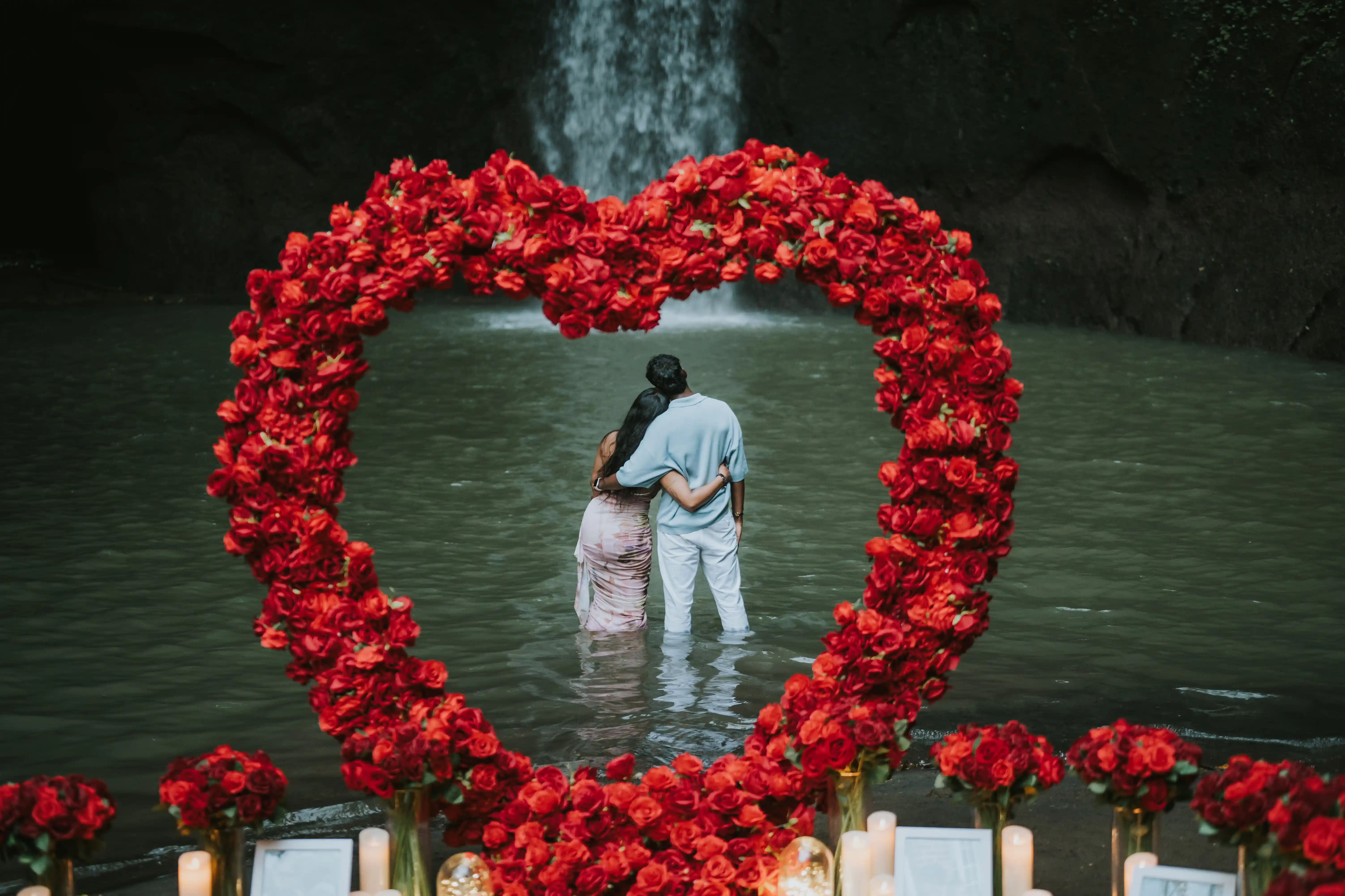 Romantic Bali waterfall proposal moment with flower heart arch