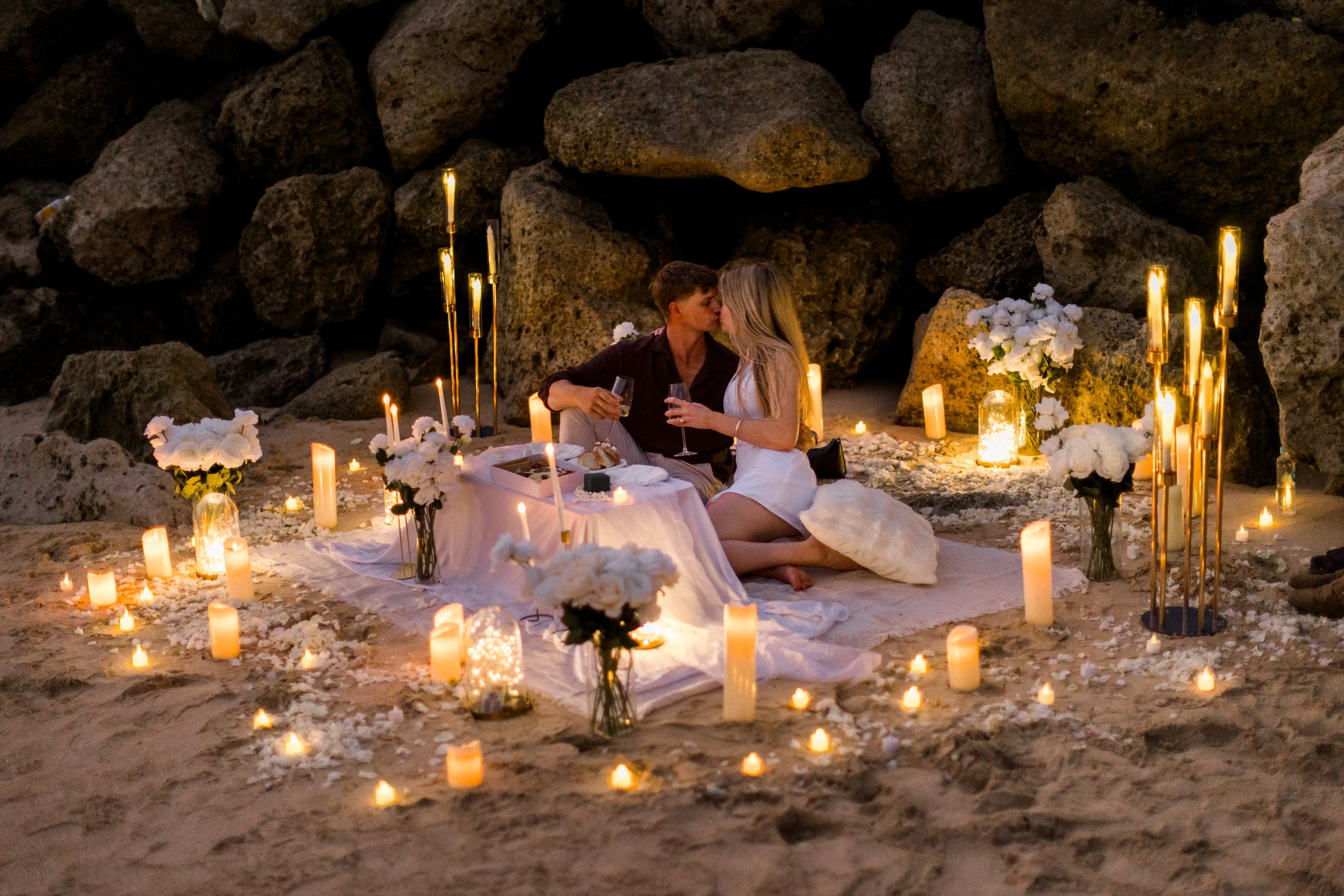 Romantic Bali beach proposal setup with candles and cozy picnic styling.