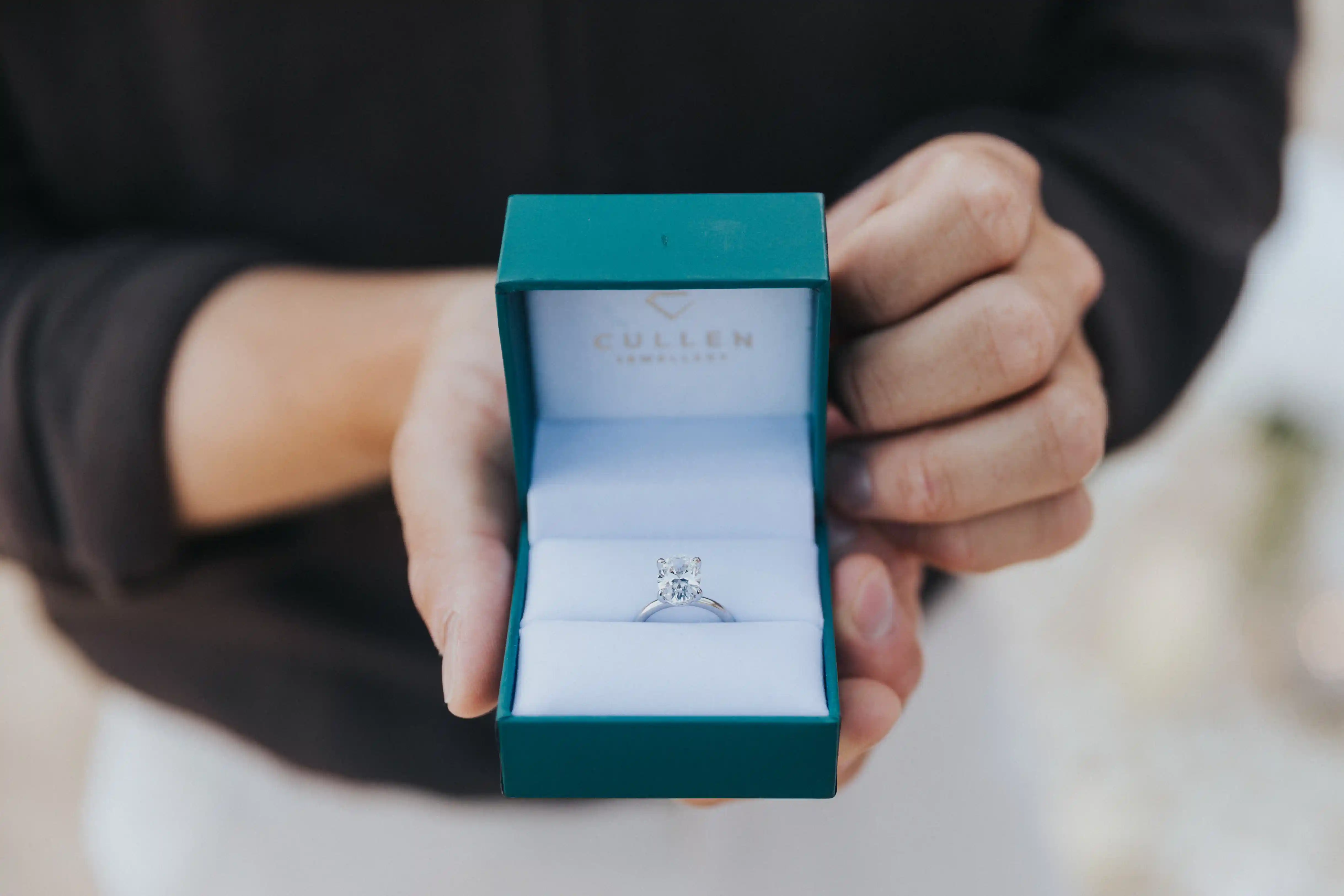 Close-up of engagement ring during romantic Bali beach proposal with soft candlelight in the background.