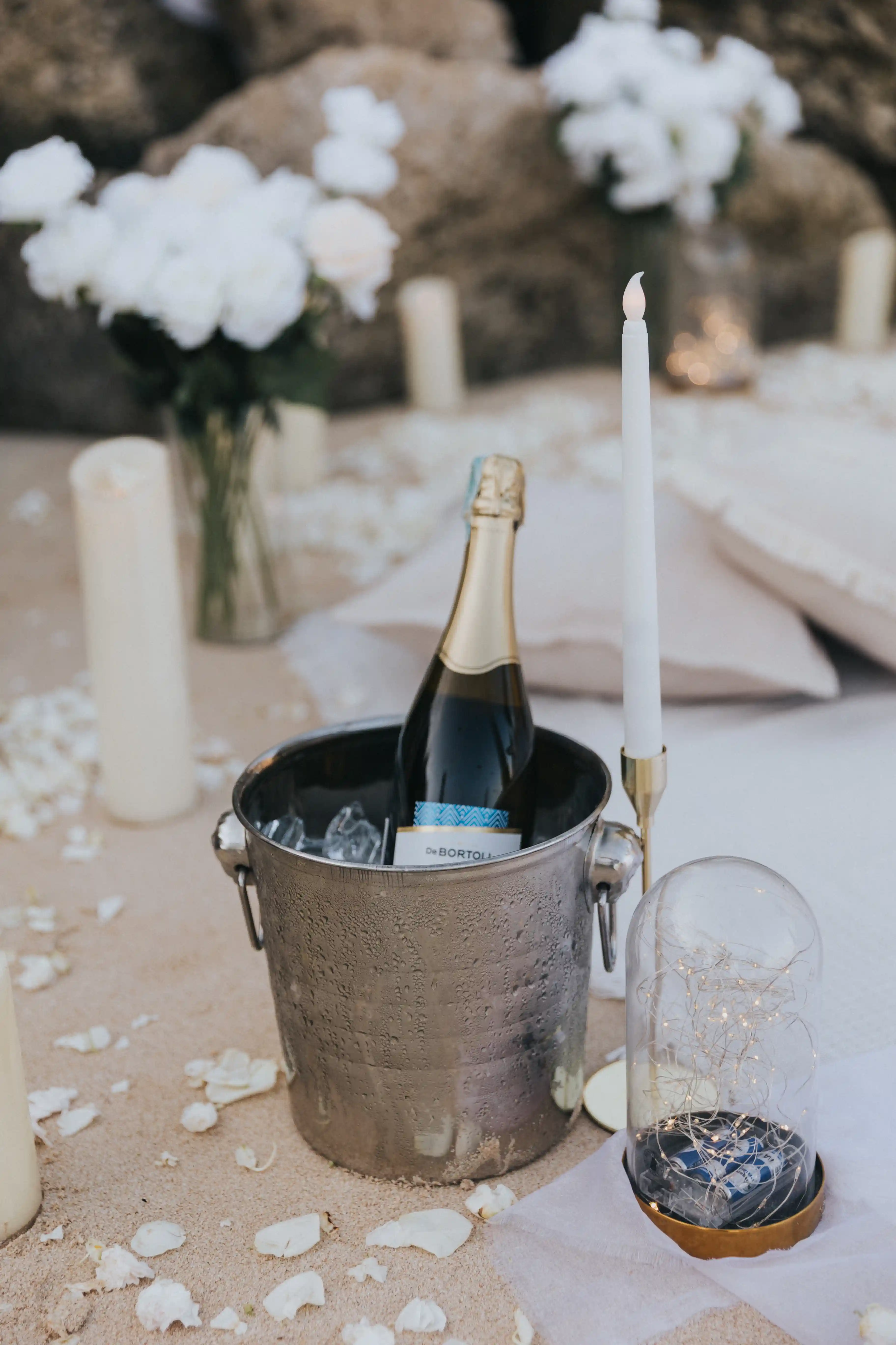 Couple celebrating their engagement with a champagne toast during a romantic Bali beach proposal at sunset.