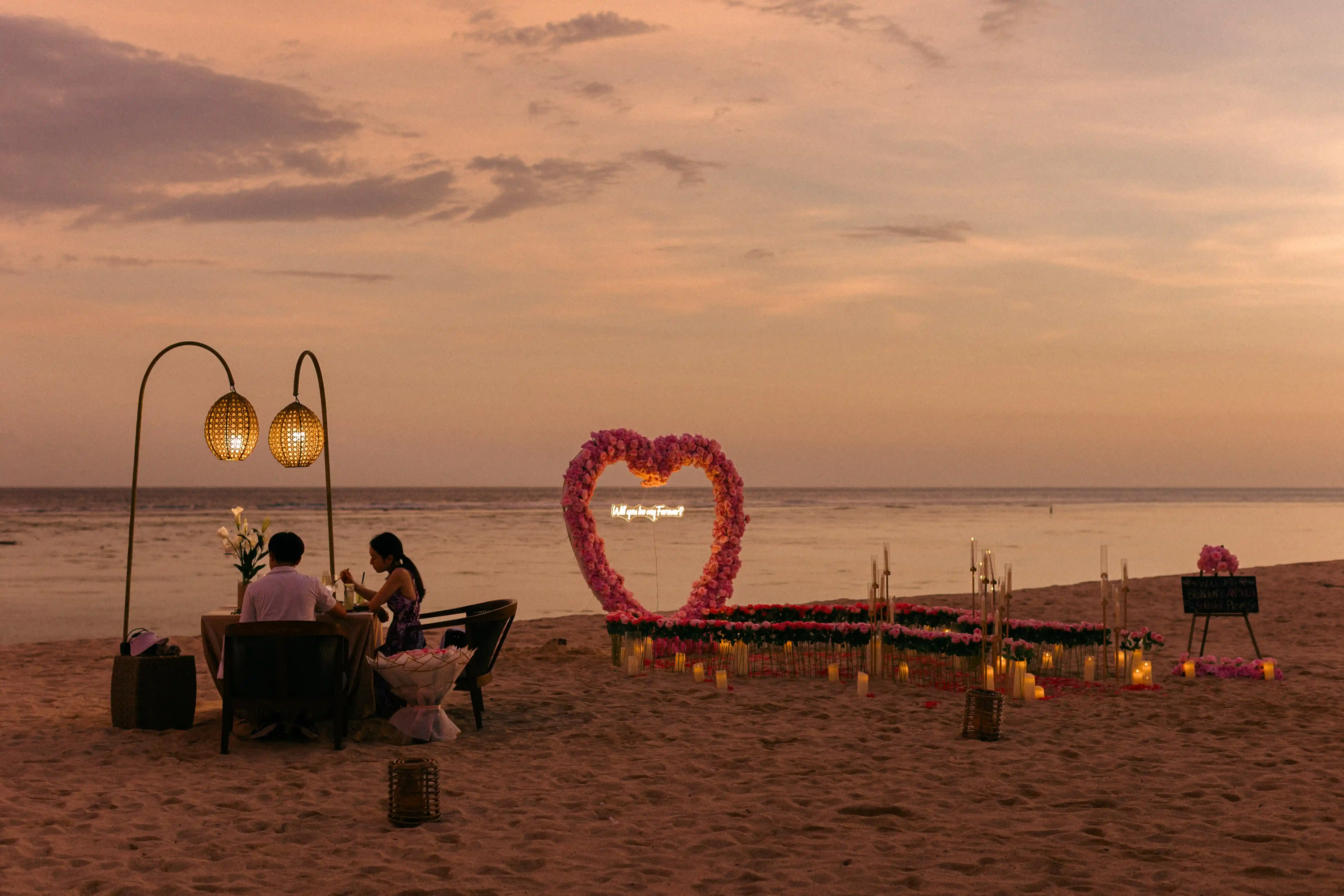 Romantic Bali proposal dinner setup with candles and pink roses.