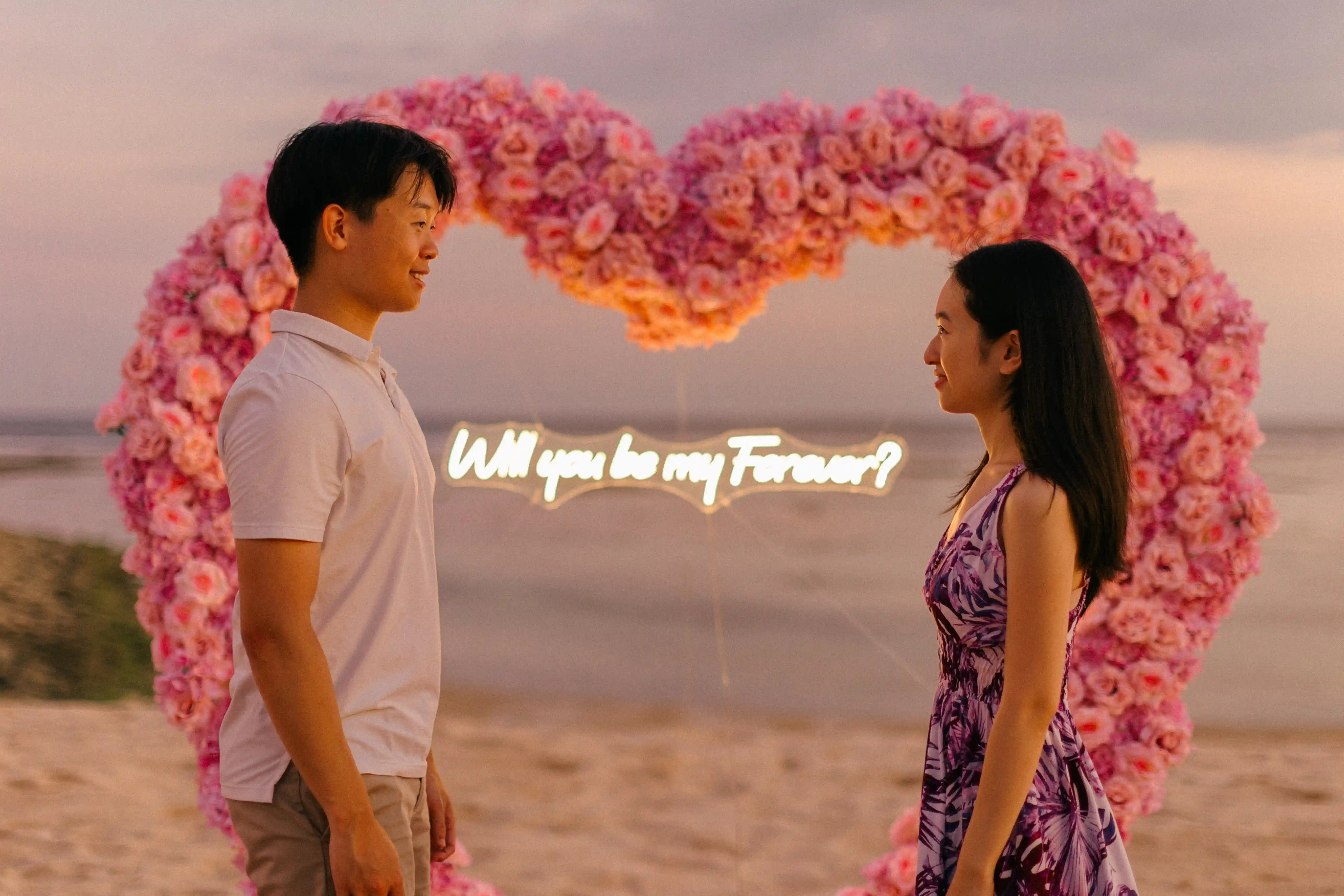 Romantic engagement moment at a Bali beach heart arch.