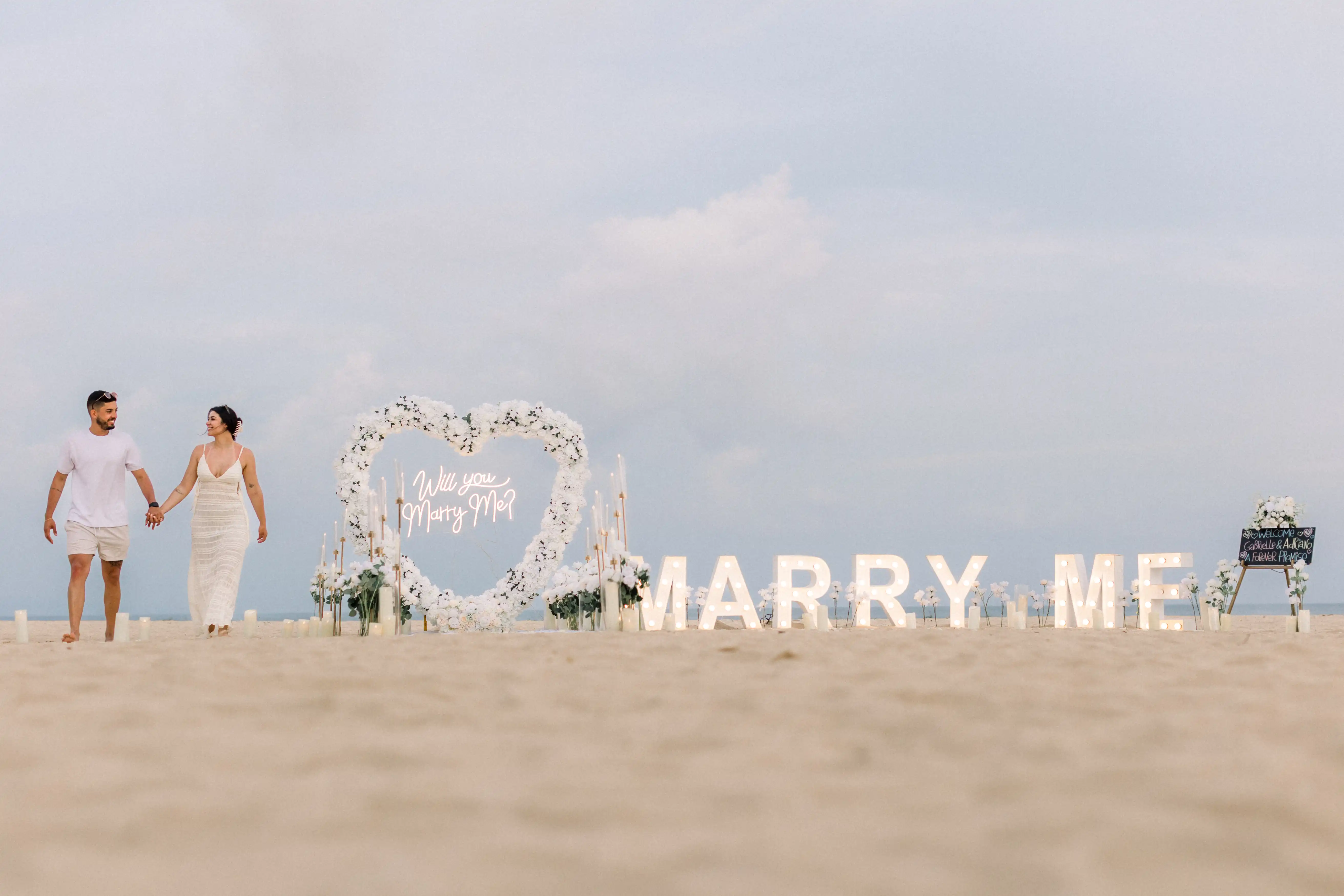 Newly engaged couple walking along Bali beach after saying yes.